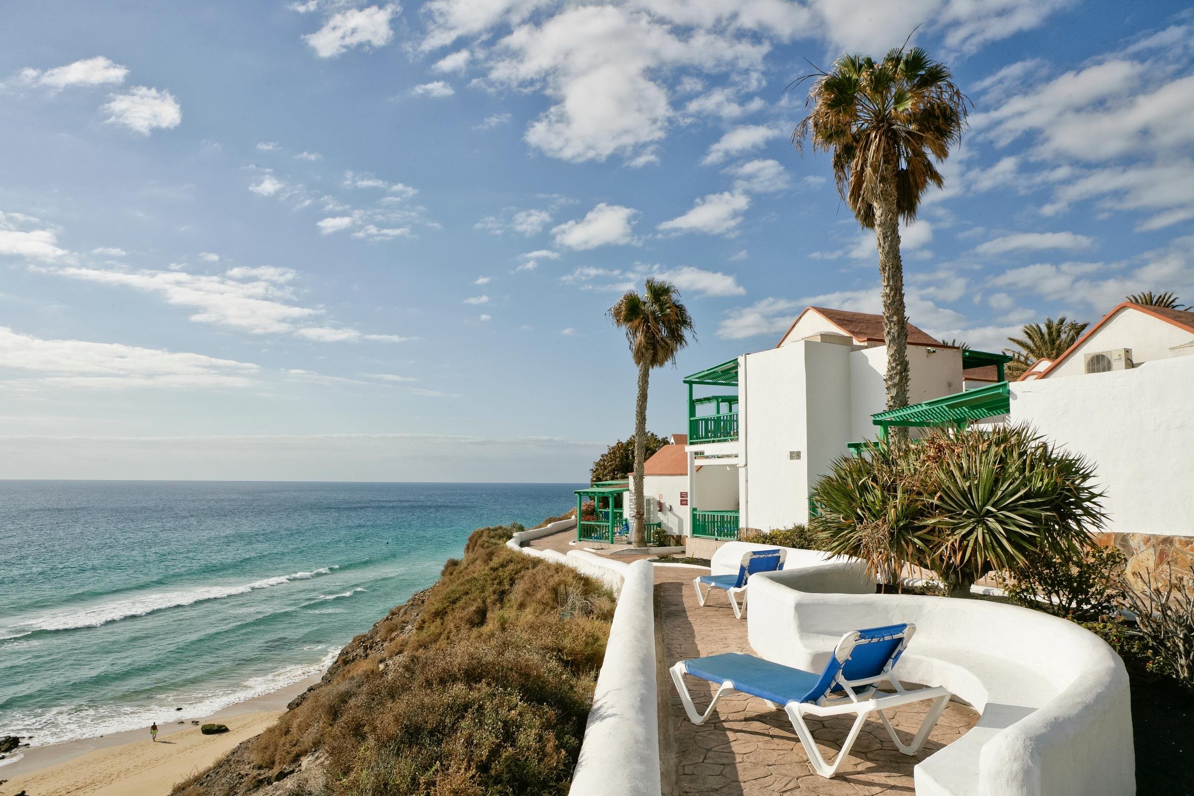 Blick auf den Strand und das Meer bei Aldiana mit Pool und Palmen, sonniges Wetter.