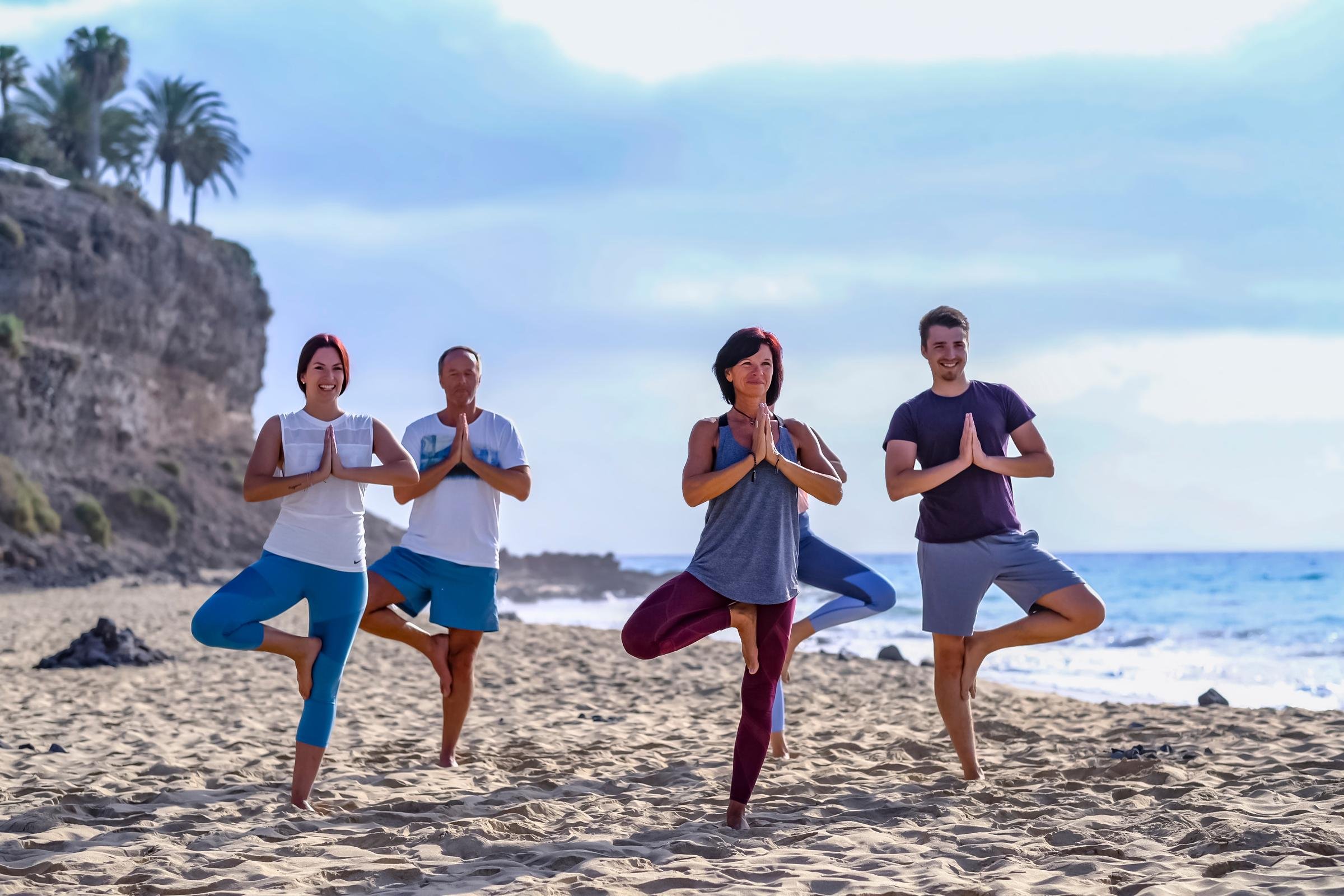 Vier Menschen machen Yoga am Strand, genießen einen Premium Cluburlaub bei Aldiana.