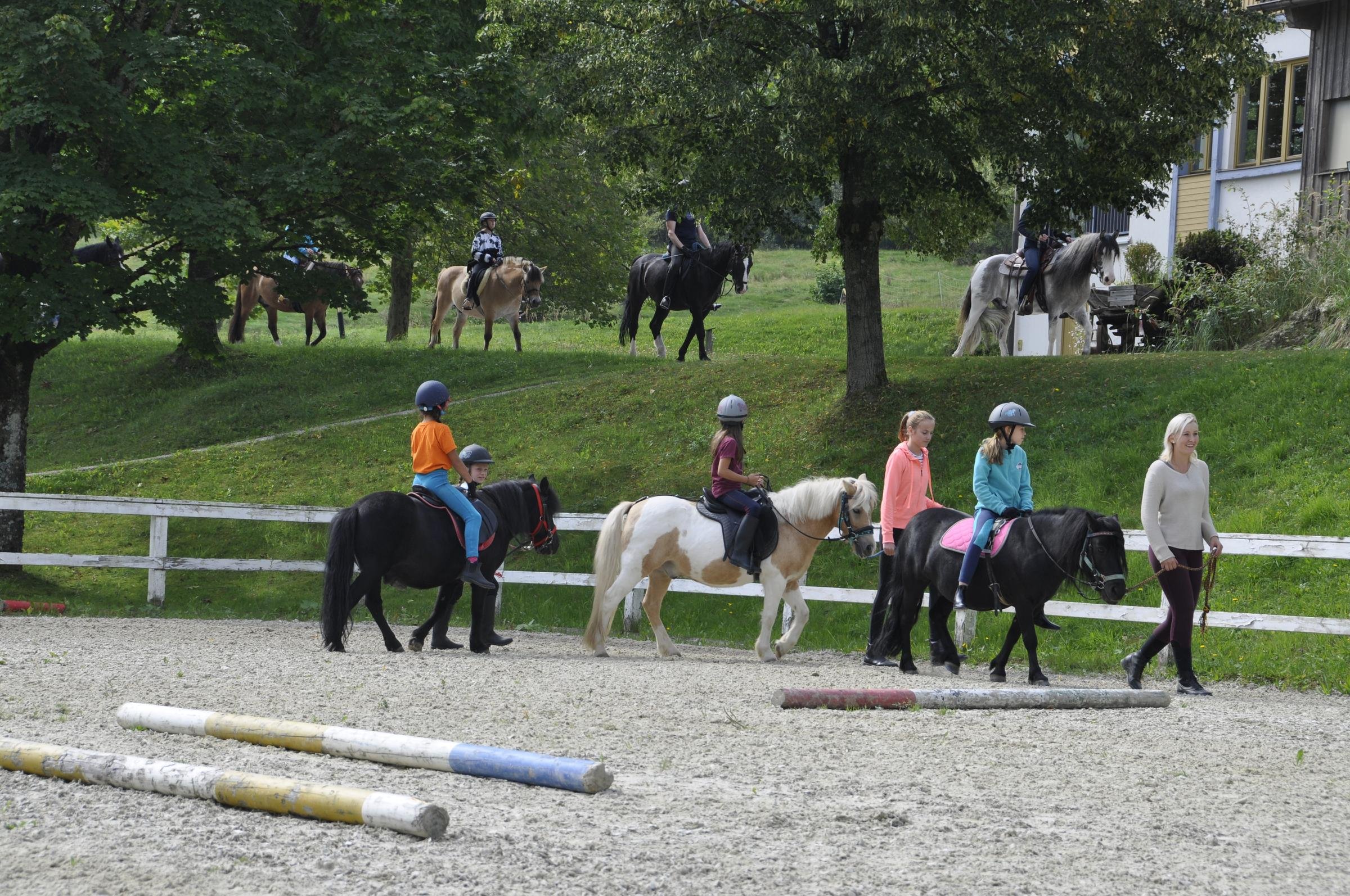 Kinder reiten auf einem Reitplatz im Grünen bei Aldiana, begleitet von Betreuern
