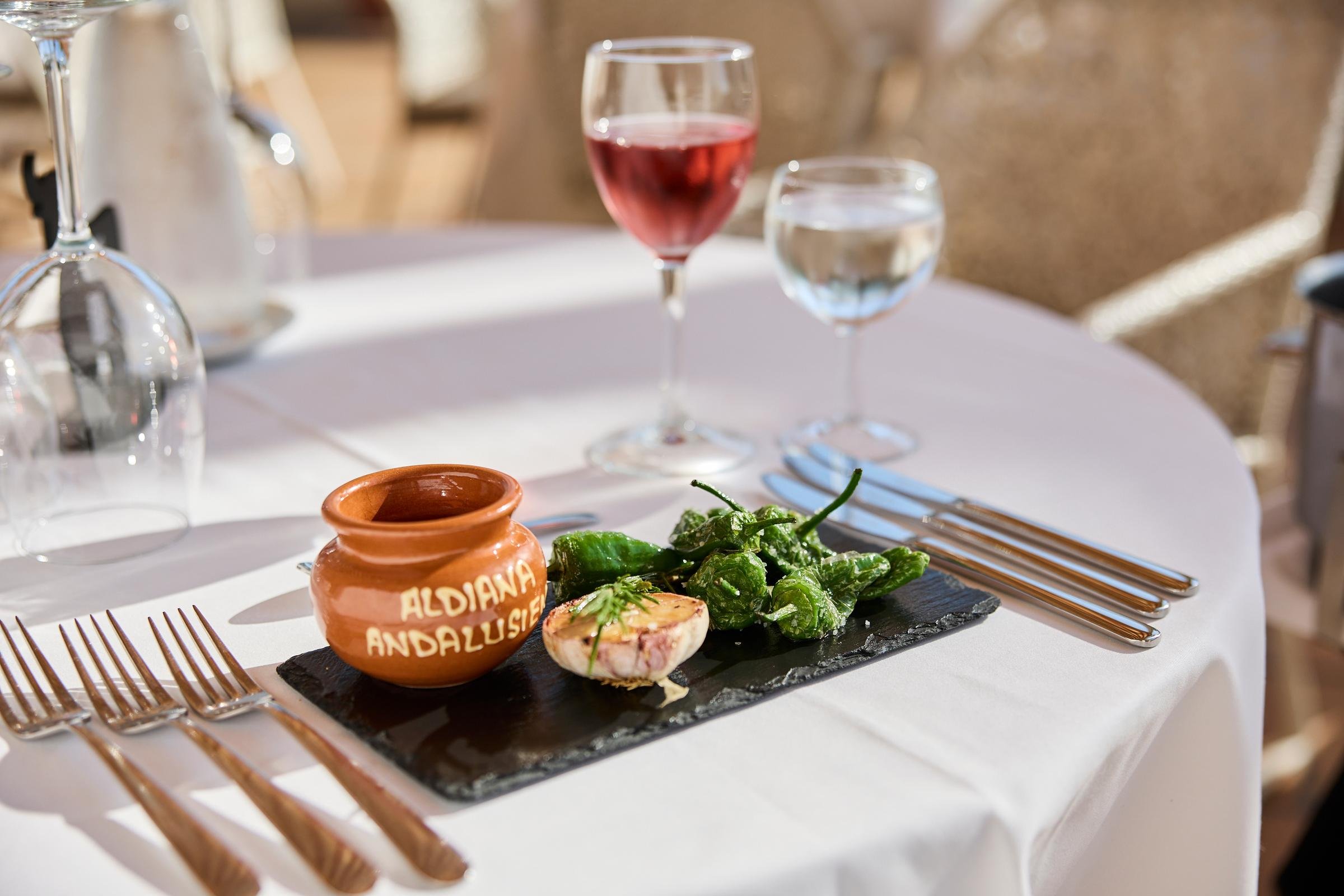 Elegantes Tischbild mit Wein, Tapas und zentraler Tontöpfer für Premium Cluburlaub bei Aldiana