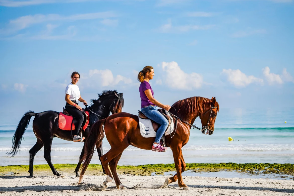 Paar reitet am Strand auf hochwertigen Pferden bei einem Premium Cluburlaub von Aldiana