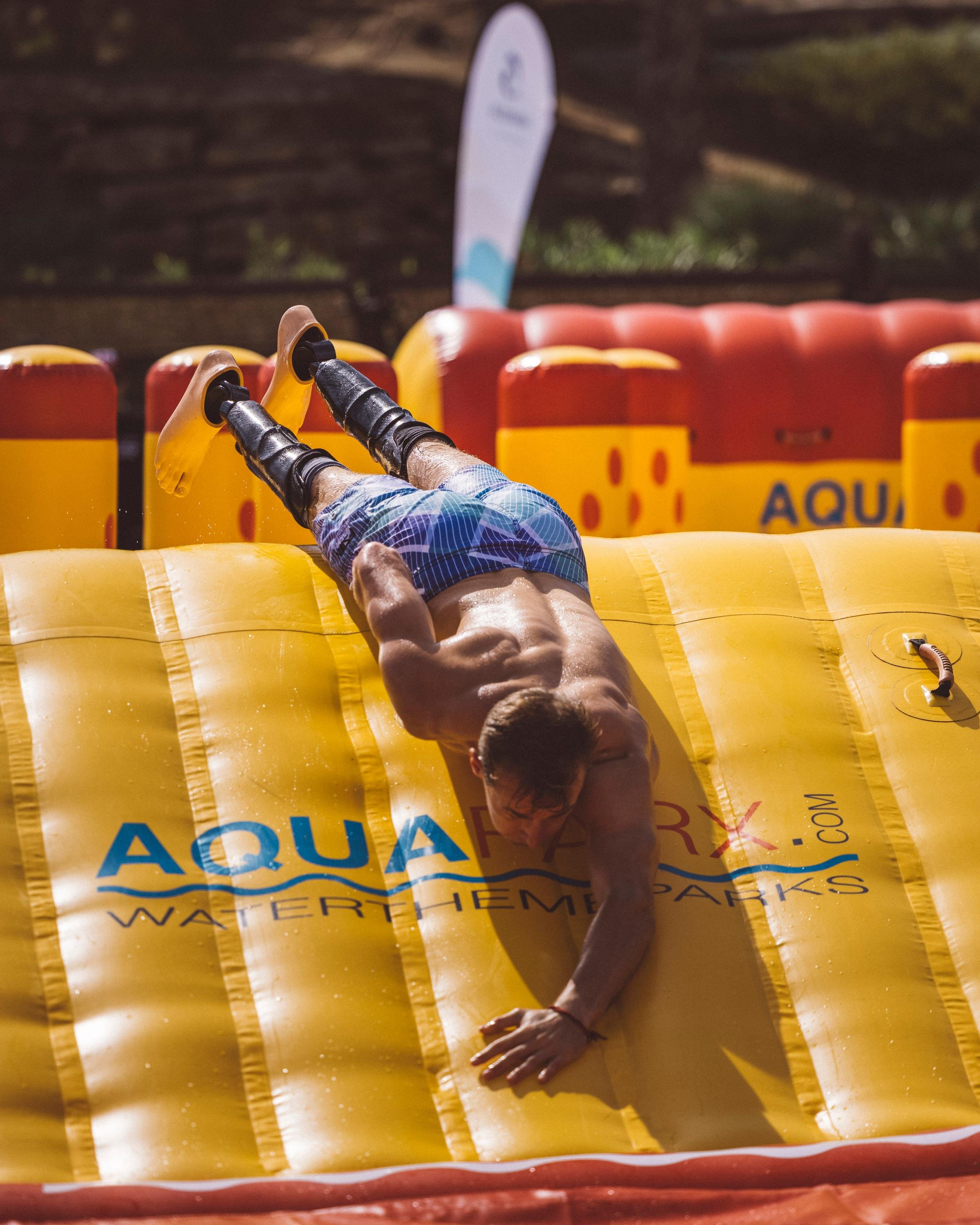 Jugendlicher bei Wasserpark-Attraktion auf einem hochwertigen, aufblasbaren Wassertrampolin
