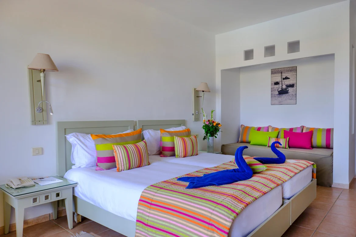 Doppelzimmer im Aldiana Club mit bunten Bettdecken und Schwanenhandtüchern auf dem Bett