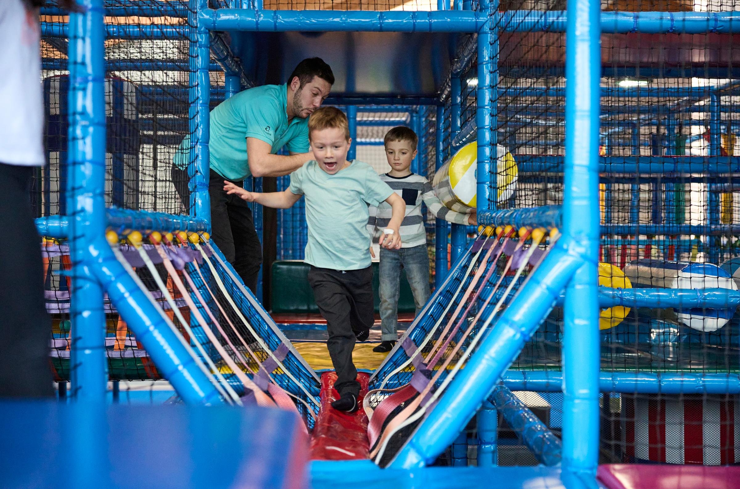 Kinder spielen auf einem bunten Indoor-Kletter- und Rutschspielplatz bei Aldiana, Premium Cluburlaub