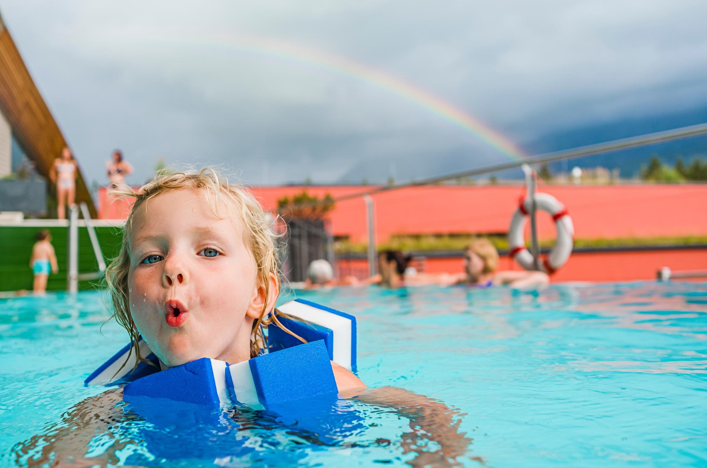 Blick auf einen Pool bei Aldiana mit Regenbogen im Himmel und entspannten Gästen