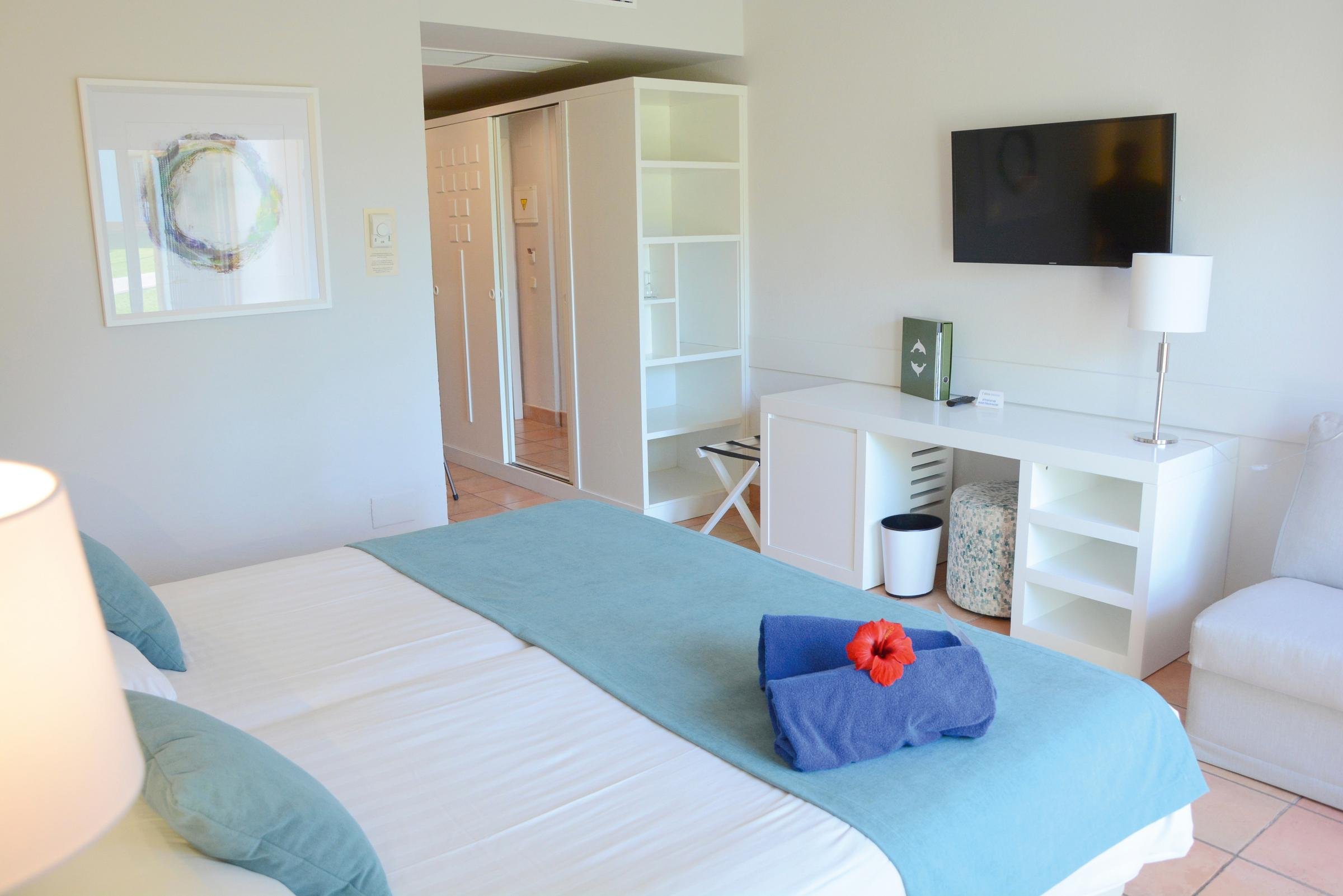 Ein modernes Hotelzimmer bei Aldiana mit Bett, Fernseher und Loungetisch.