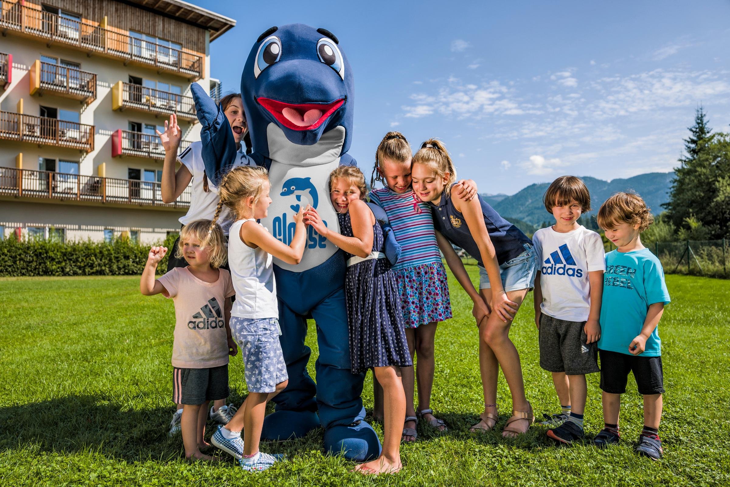 Familiengruppe mit Kindermaskottchen auf Wiese bei Aldiana Premium Cluburlaub