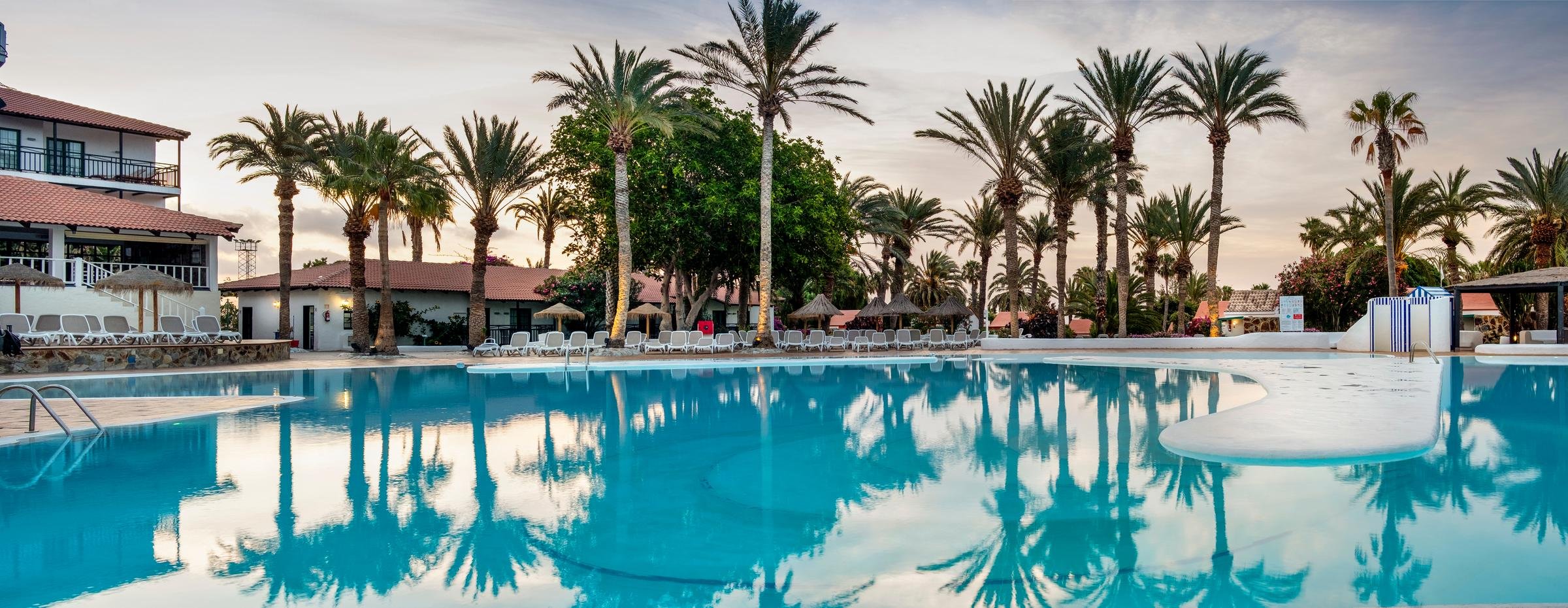 Aldiana Resort Pool mit Palmen, Liegen und sonnigem Himmel, ideal für Erholung und Entspannung