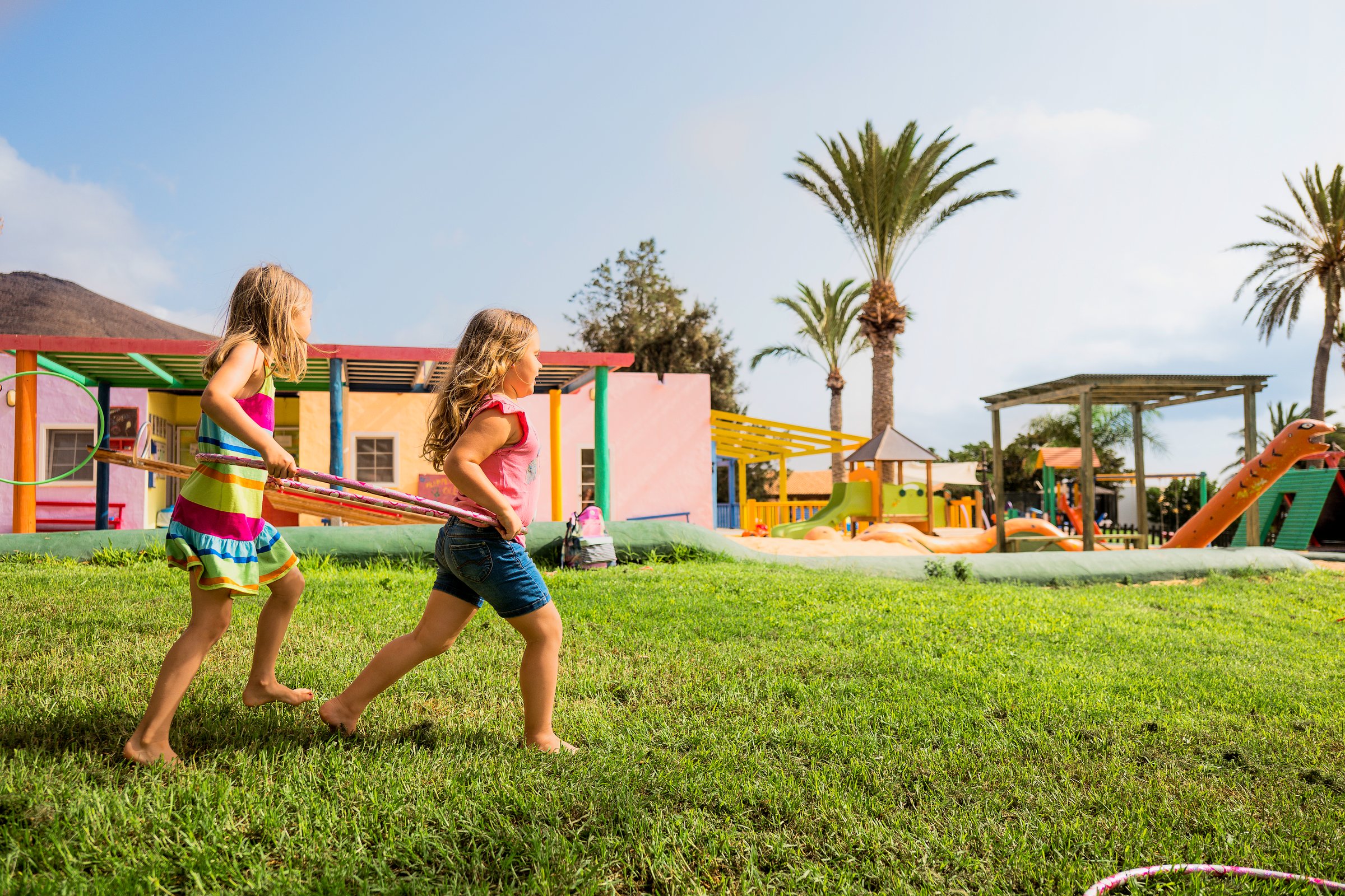 Zwei Kinder spielen fröhlich auf einem Spielplatz im sonnigen Aldiana Premium Cluburlaub