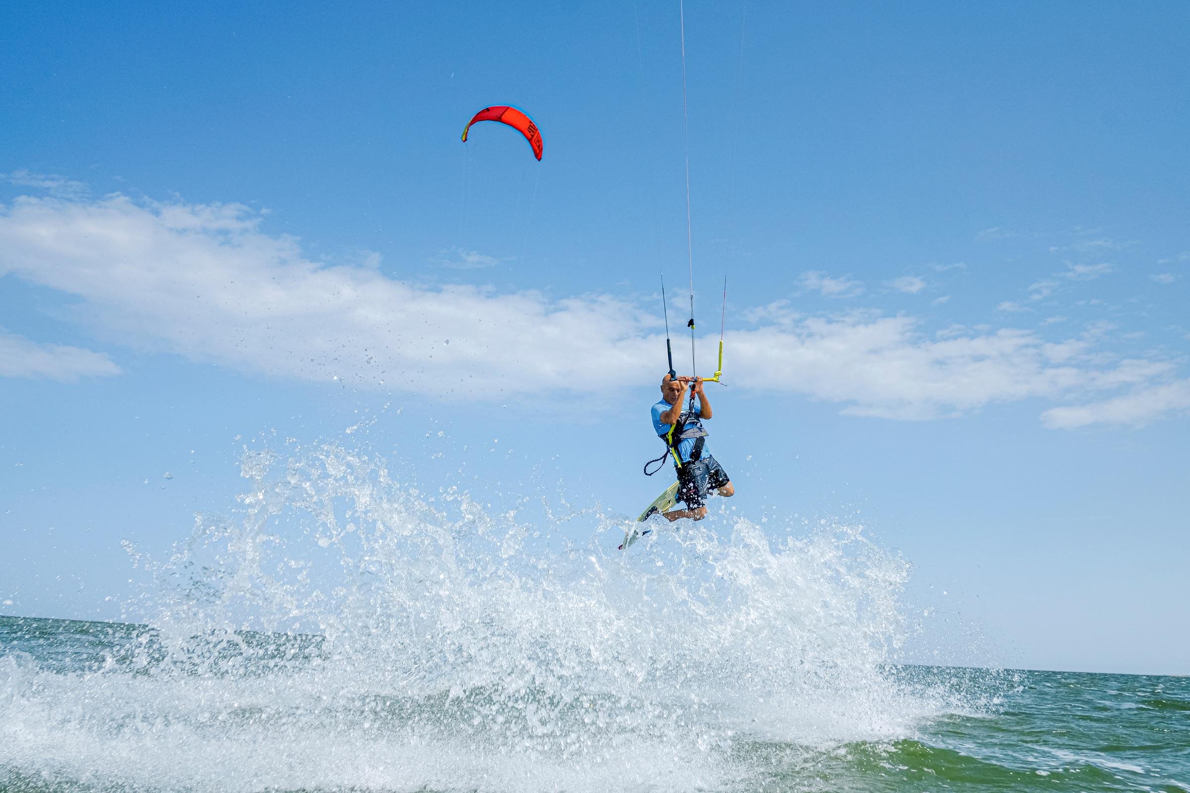 Kitesurfer in blauem Anzug mit Gelbrucksack, aktiv auf dem Meer bei schönem Himmel