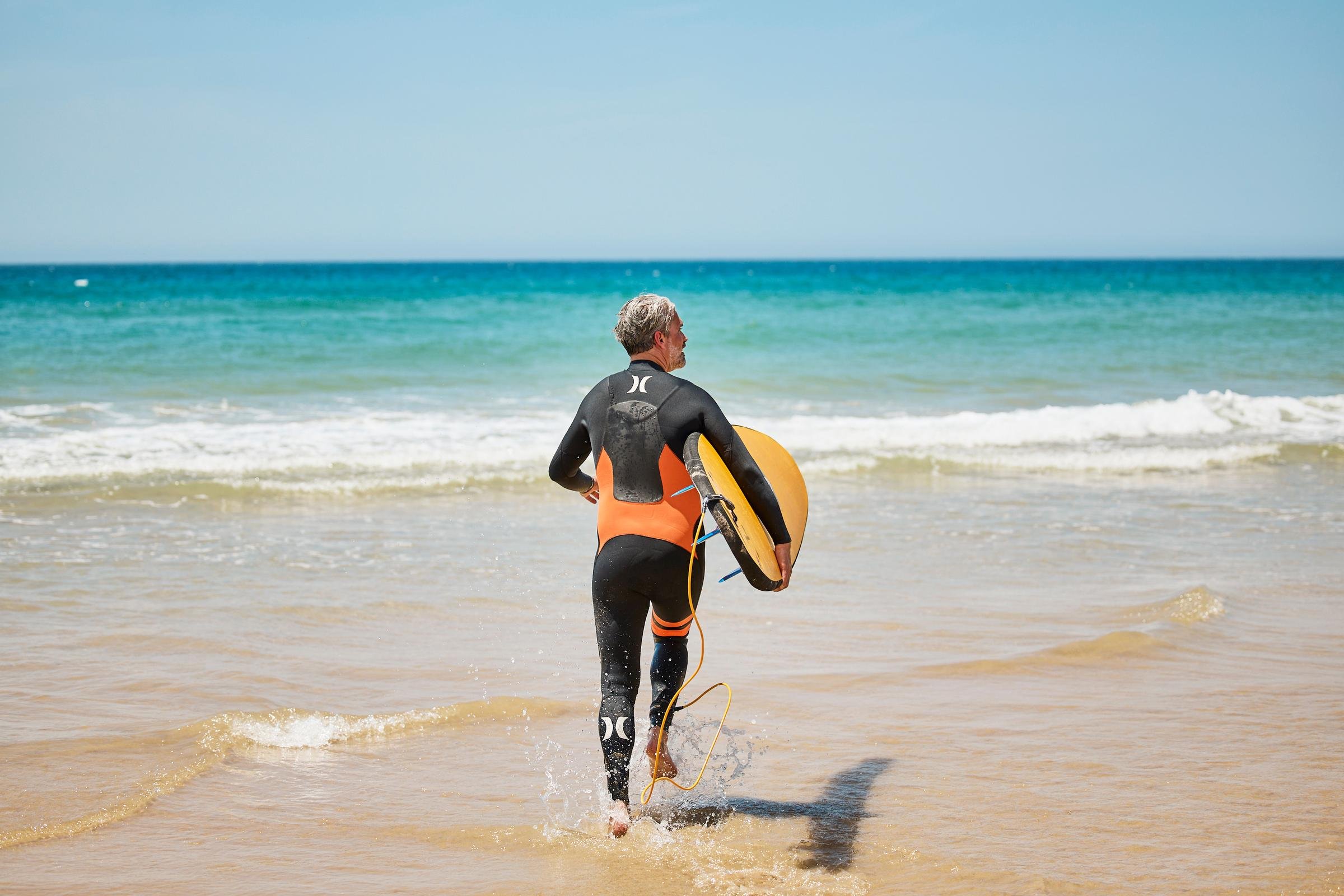 Mensch mit Surfboard am Strand 