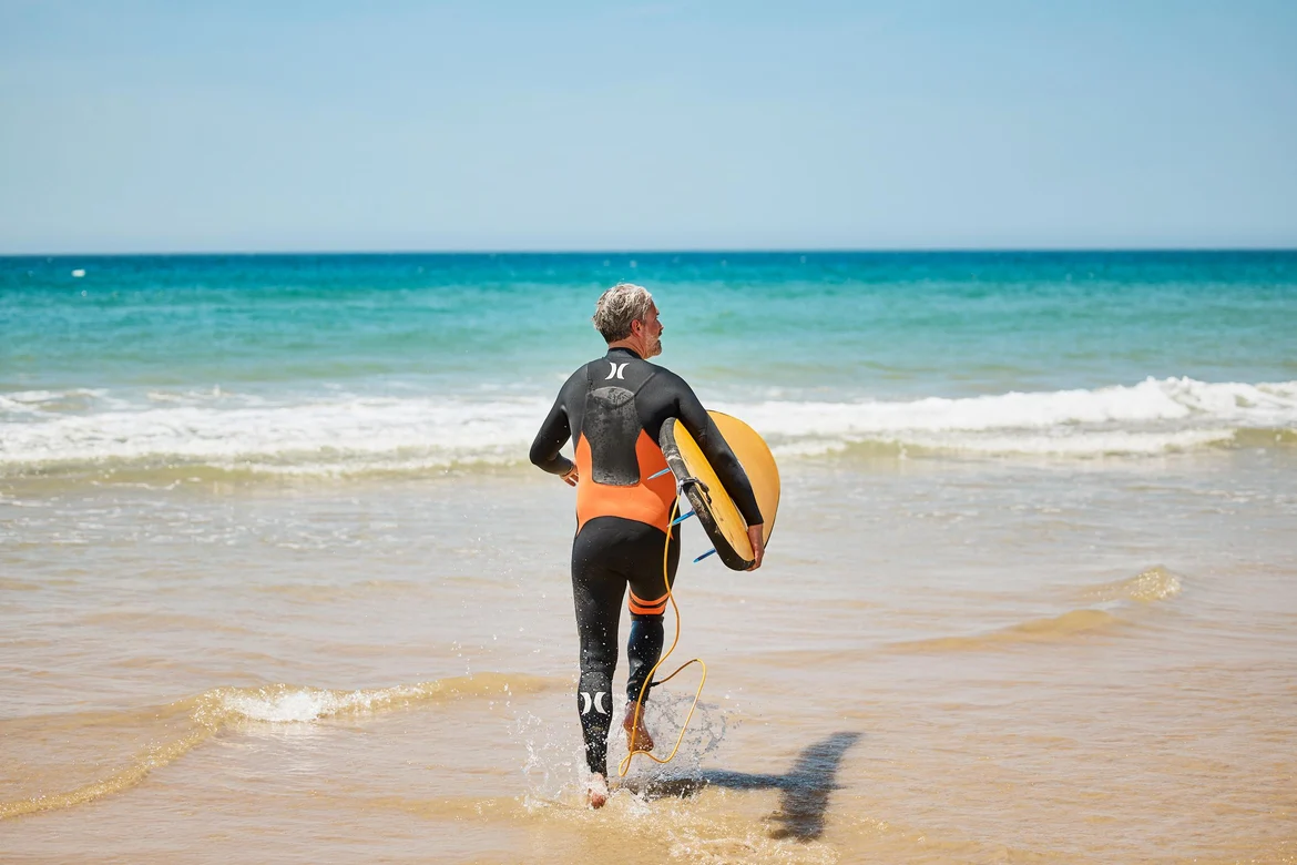 Mensch mit Surfboard am Strand 