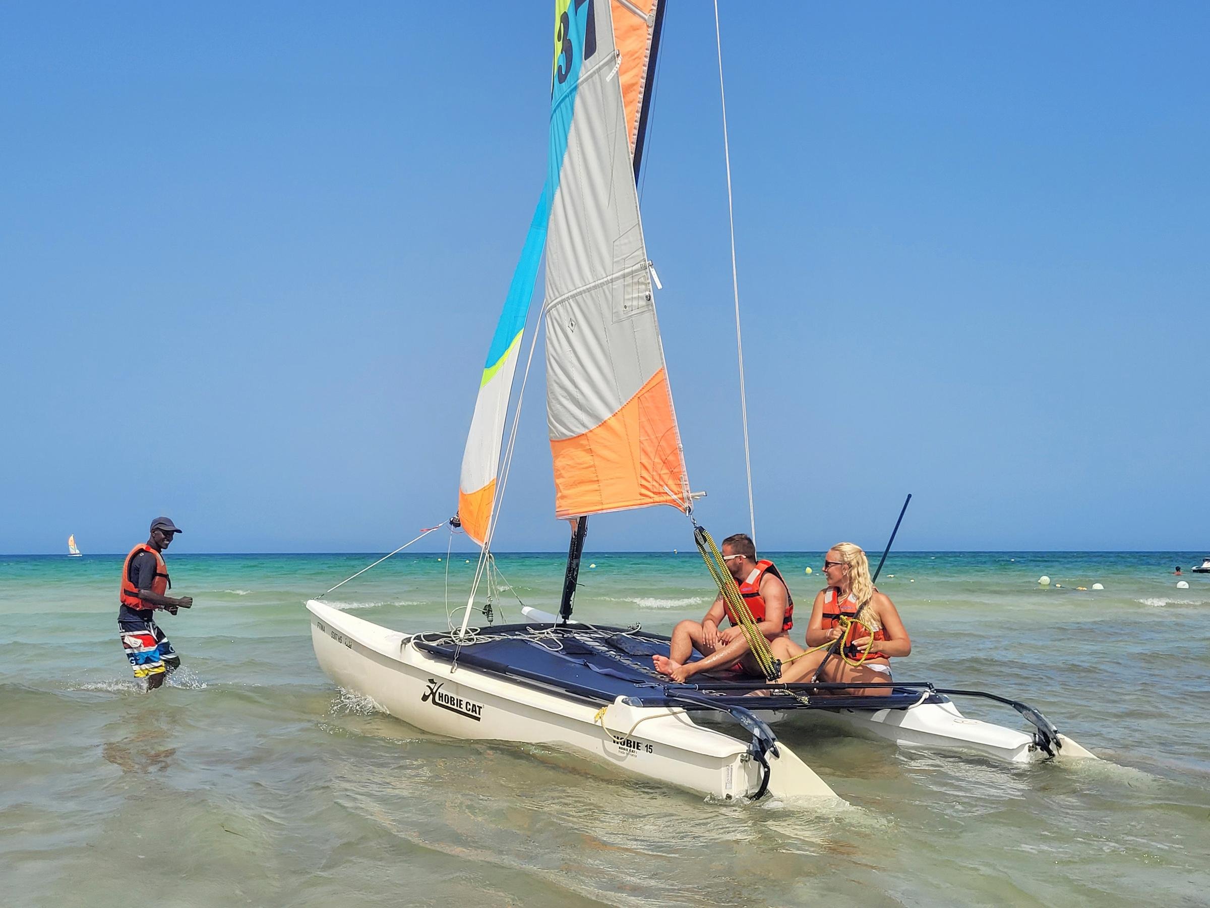 Zwei Erwachsene und ein Kind auf einem Segelboot im Meer, Spaß beim Wassersport.