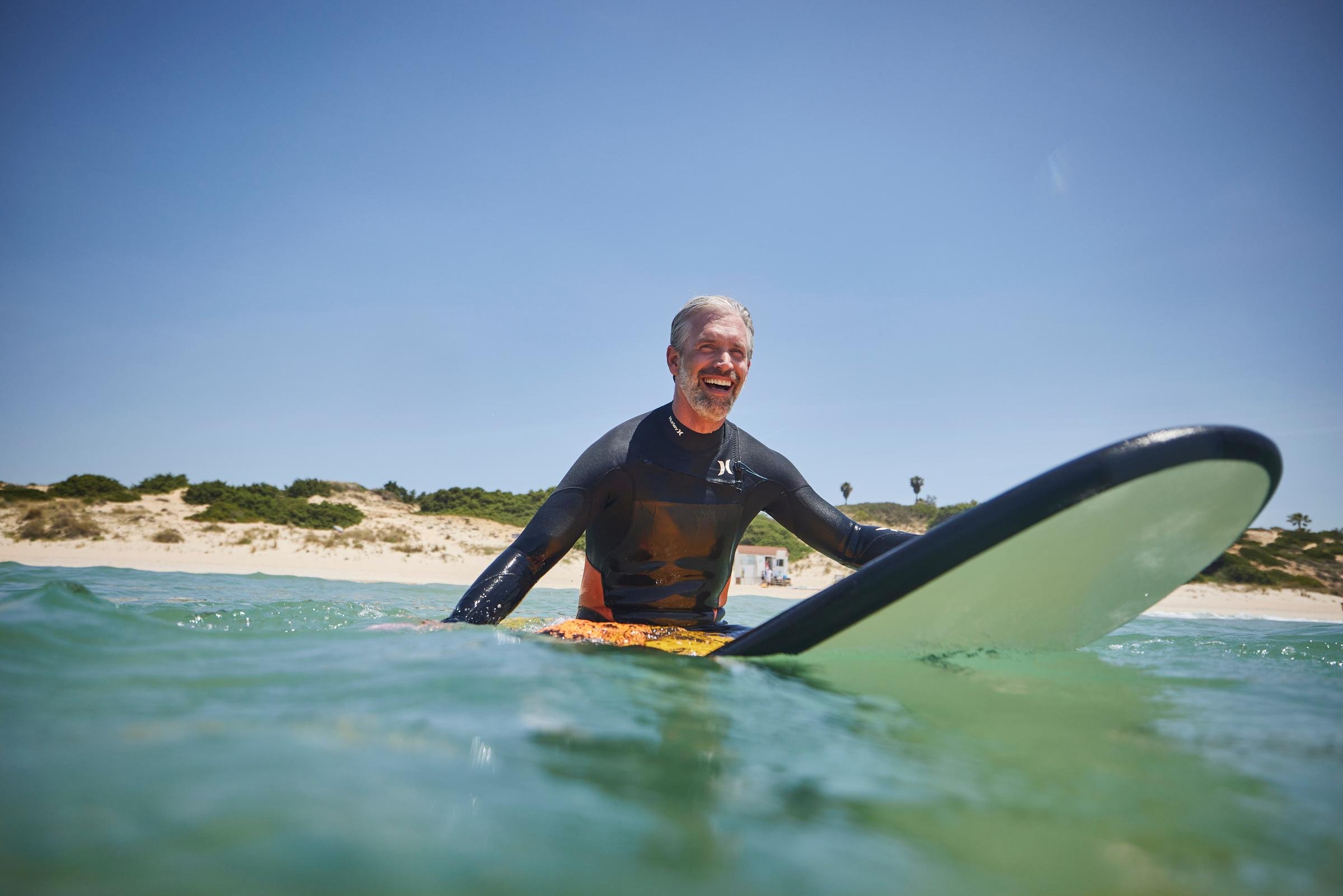 Mann beim Surfen im Meer an einem sonnigen Strand, entspannter Premium Cluburlaub