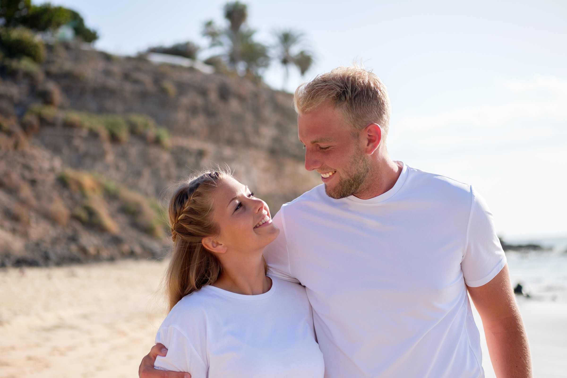 Ein Paar am Strand mit Blick auf die Küste, entspannt im Premium Cluburlaub bei Aldiana