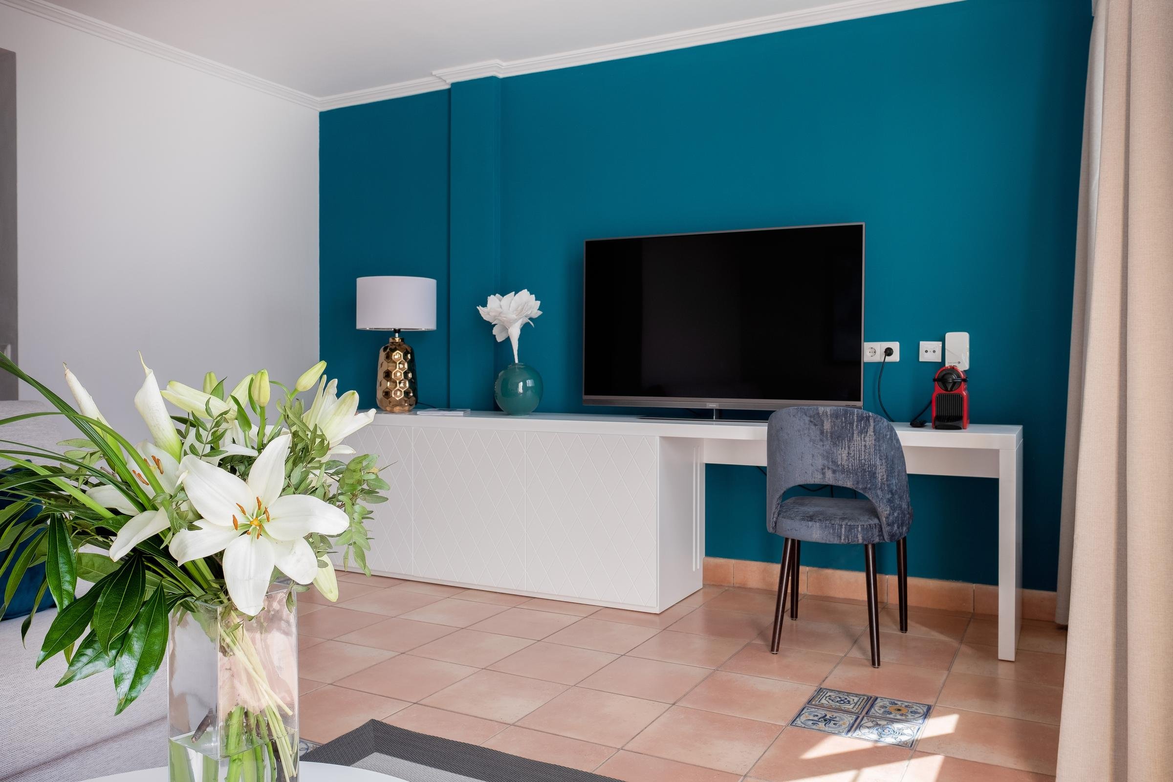 Ein modernes Zimmer mit TV, Lampen und Pflanzen für einen angenehmen Aufenthalt.