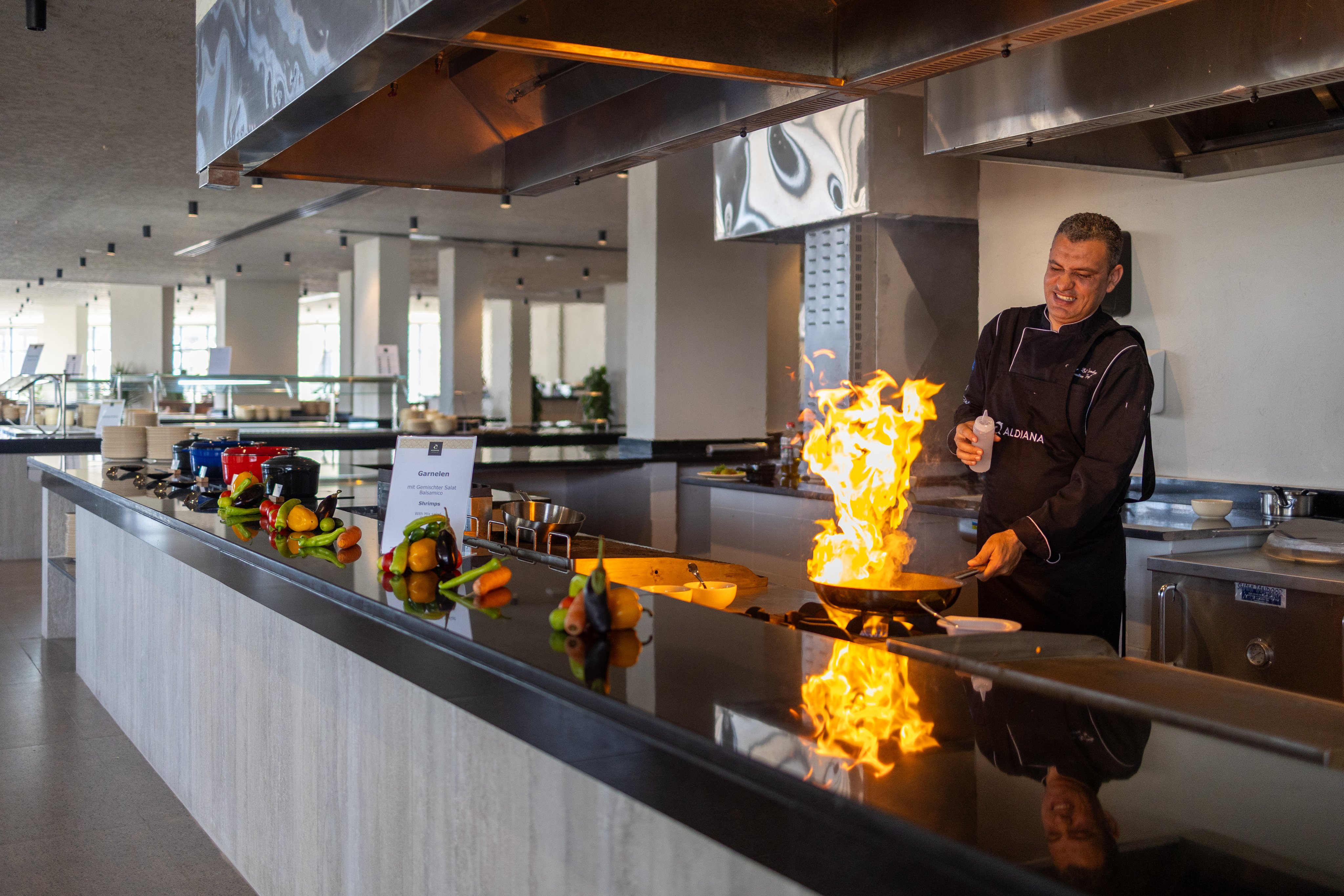 Koch in einem modernen Restaurant bei der Zubereitung eines Flambé-Gerichts, hochwertige Atmosphäre