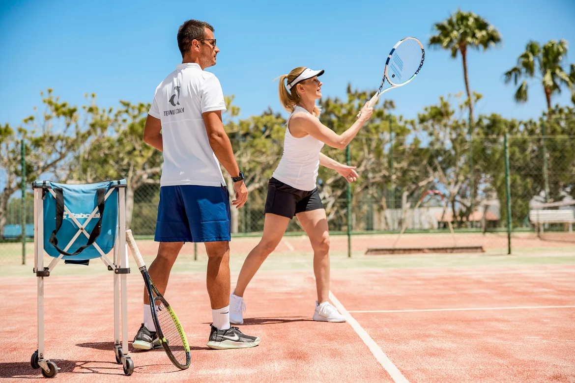 Person mit Trainer am Tennisspielen
