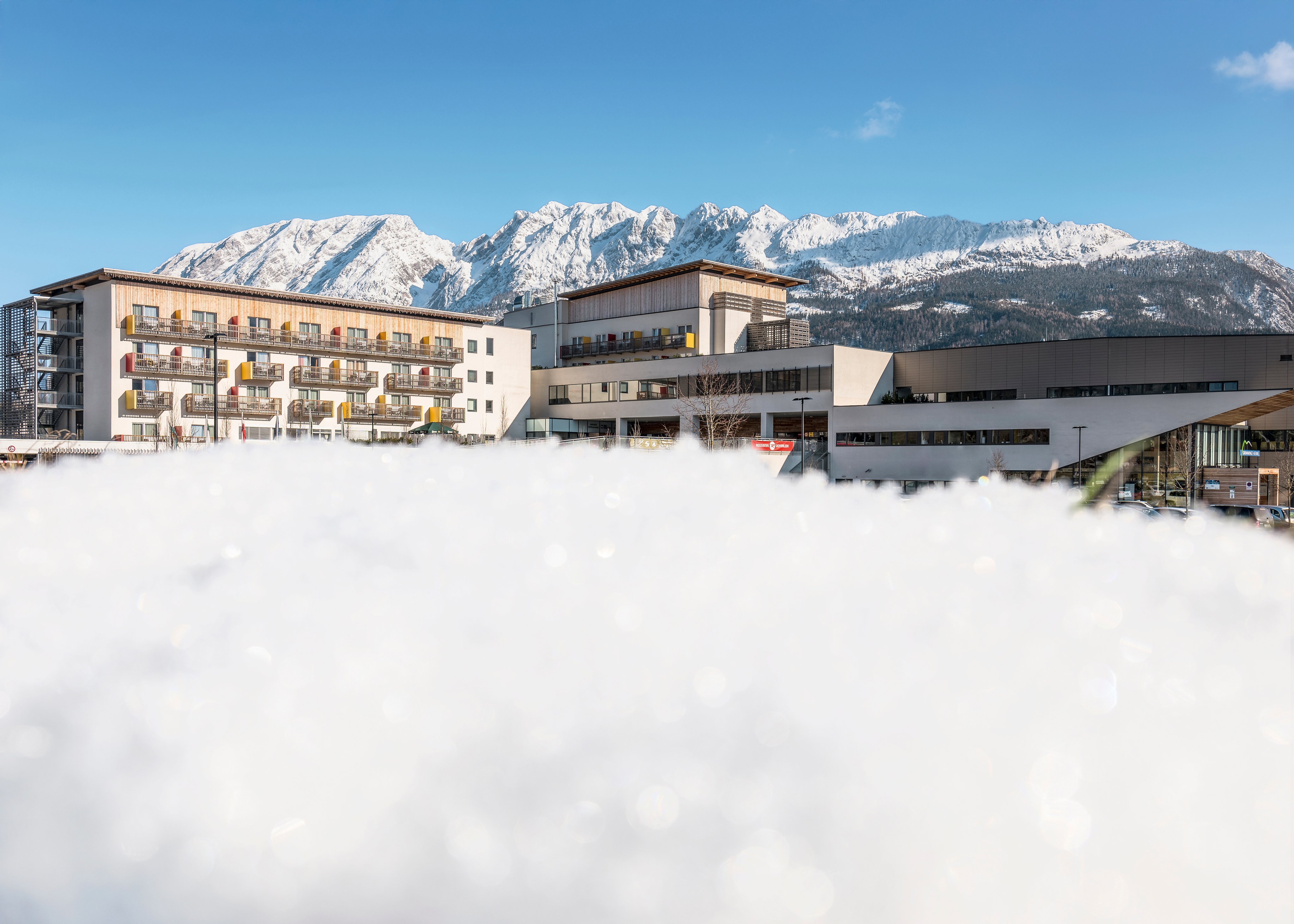 Blick auf ein modernes Hotel im Winter vor verschneiten Bergen, Ideal für Premium Cluburlaub