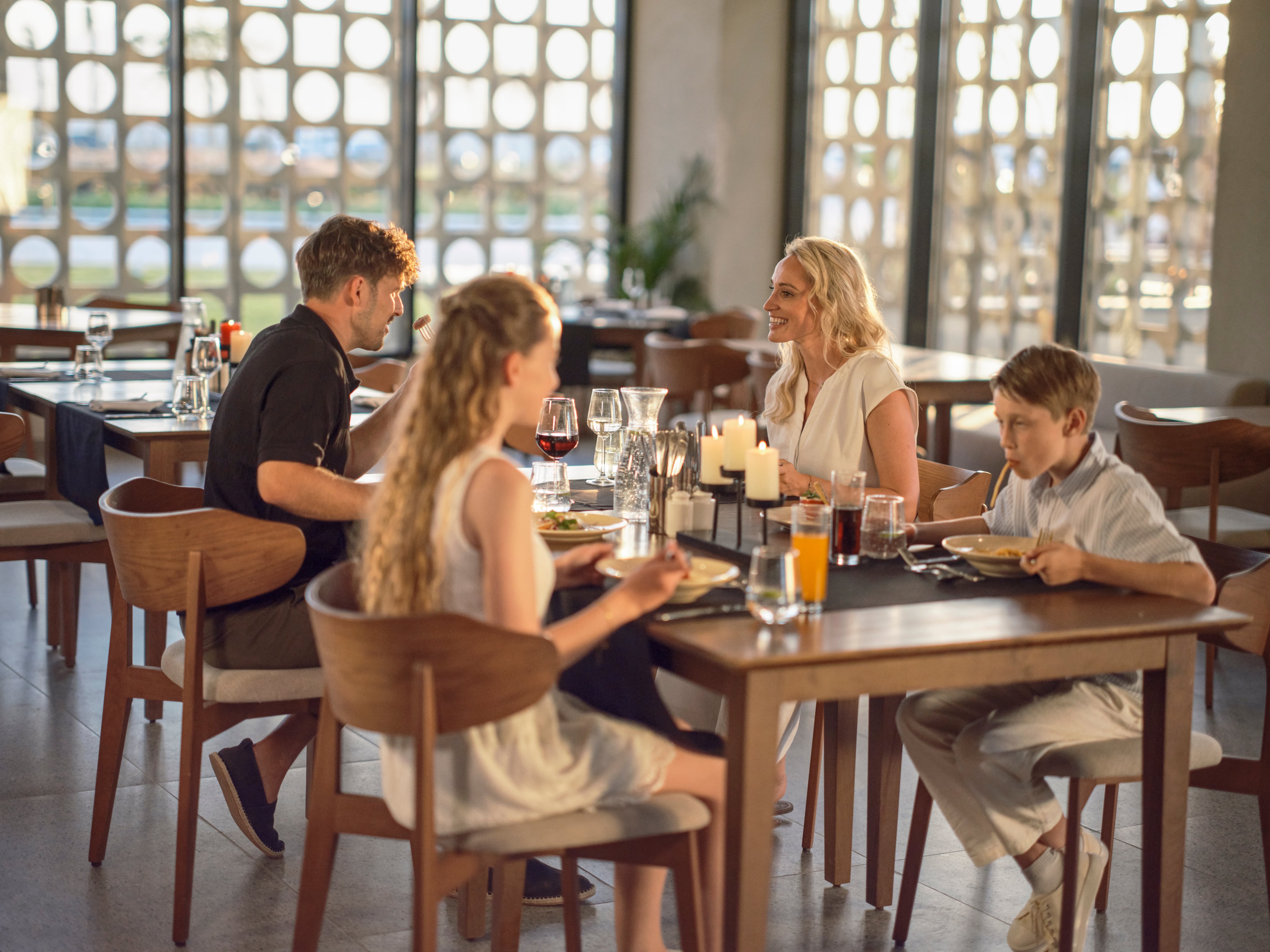 Familien beim Essen im eleganten Aldiana Clubrestaurant, entspannte Atmosphäre, große Fenster