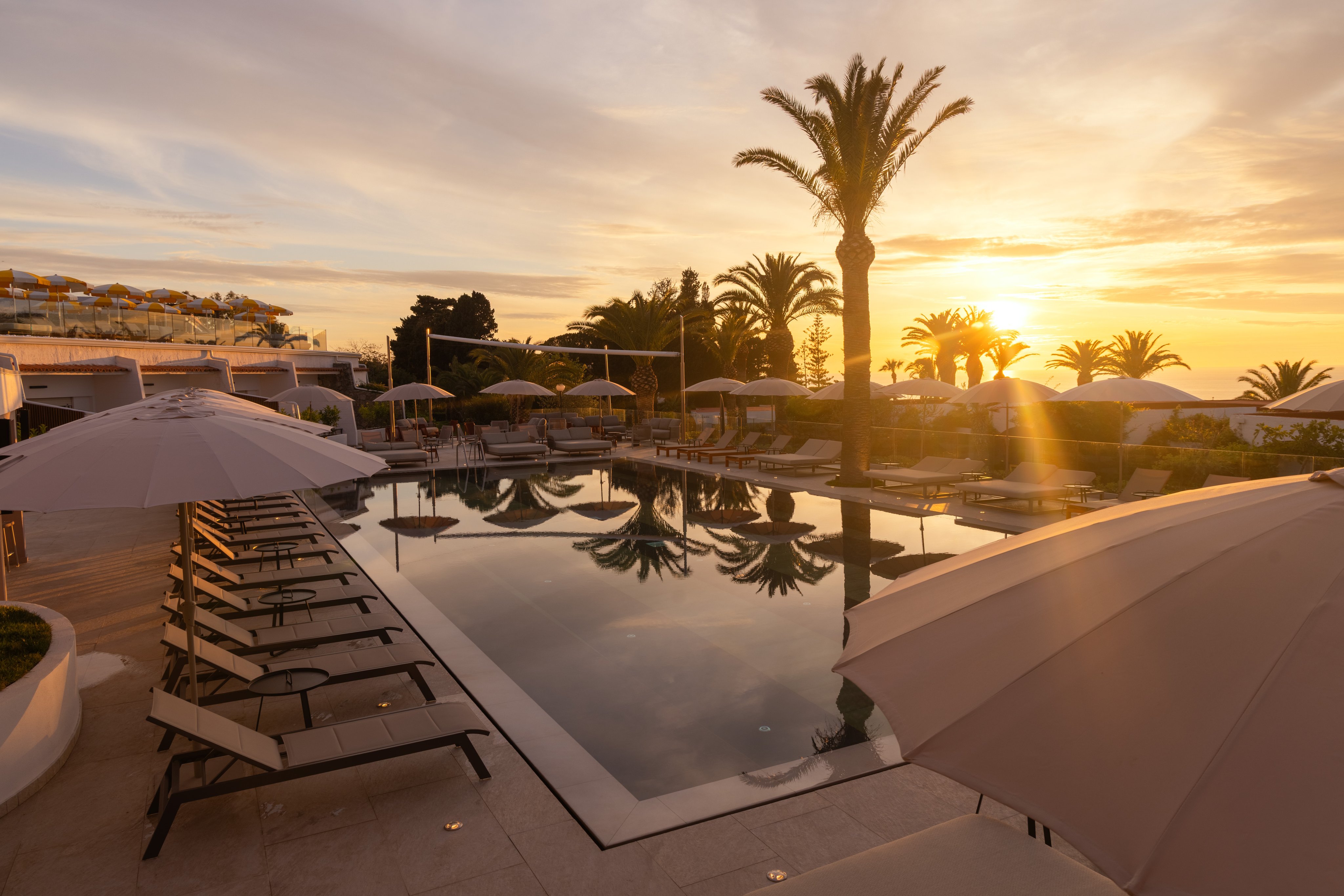 Ein eleganter Poolbereich bei Sonnenuntergang mit Palmen und Liegen, entspannte Urlaubsstimmung