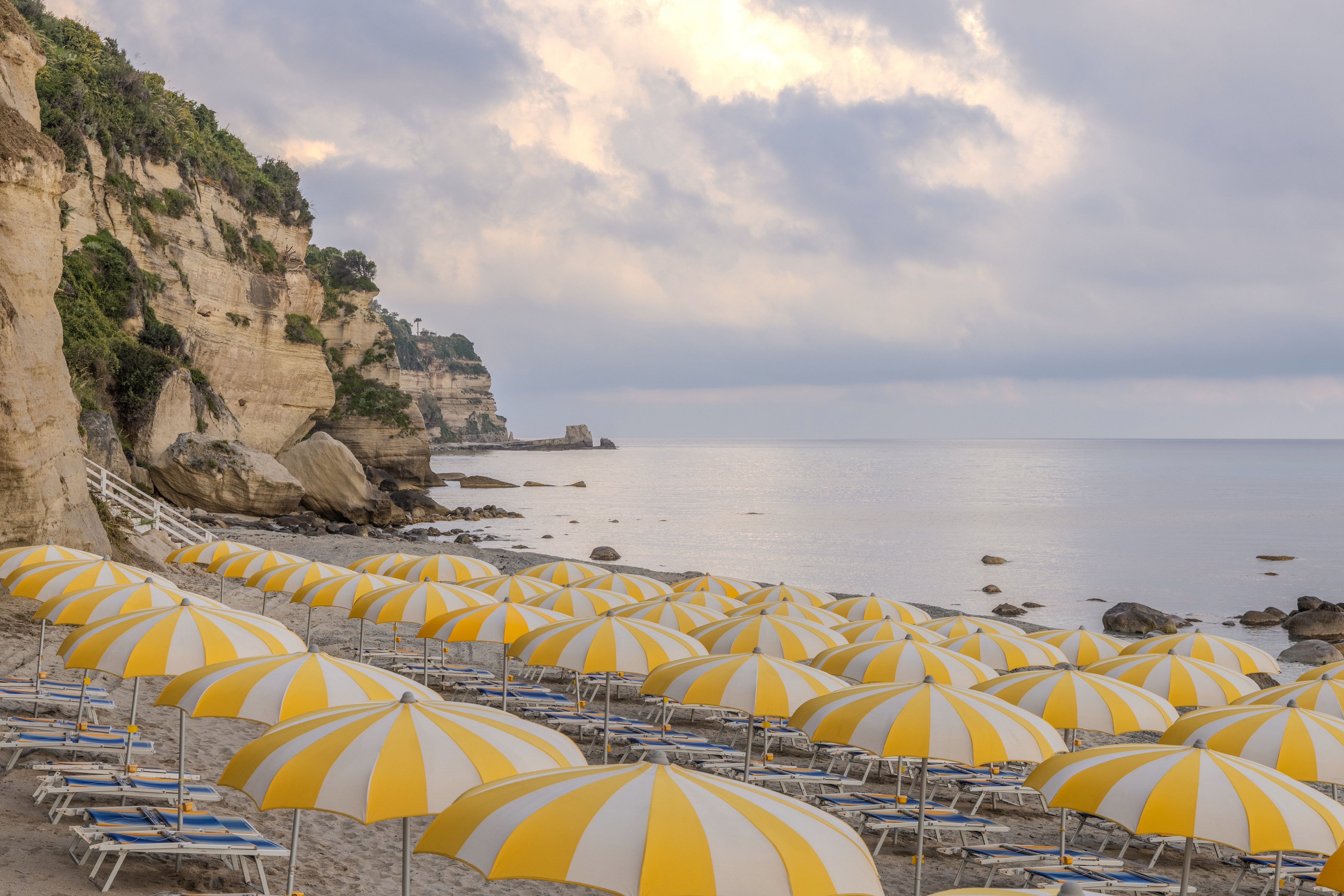 Blick auf einen Premium Cluburlaubstrand mit gelben Sonnenschirm und Meeresblick