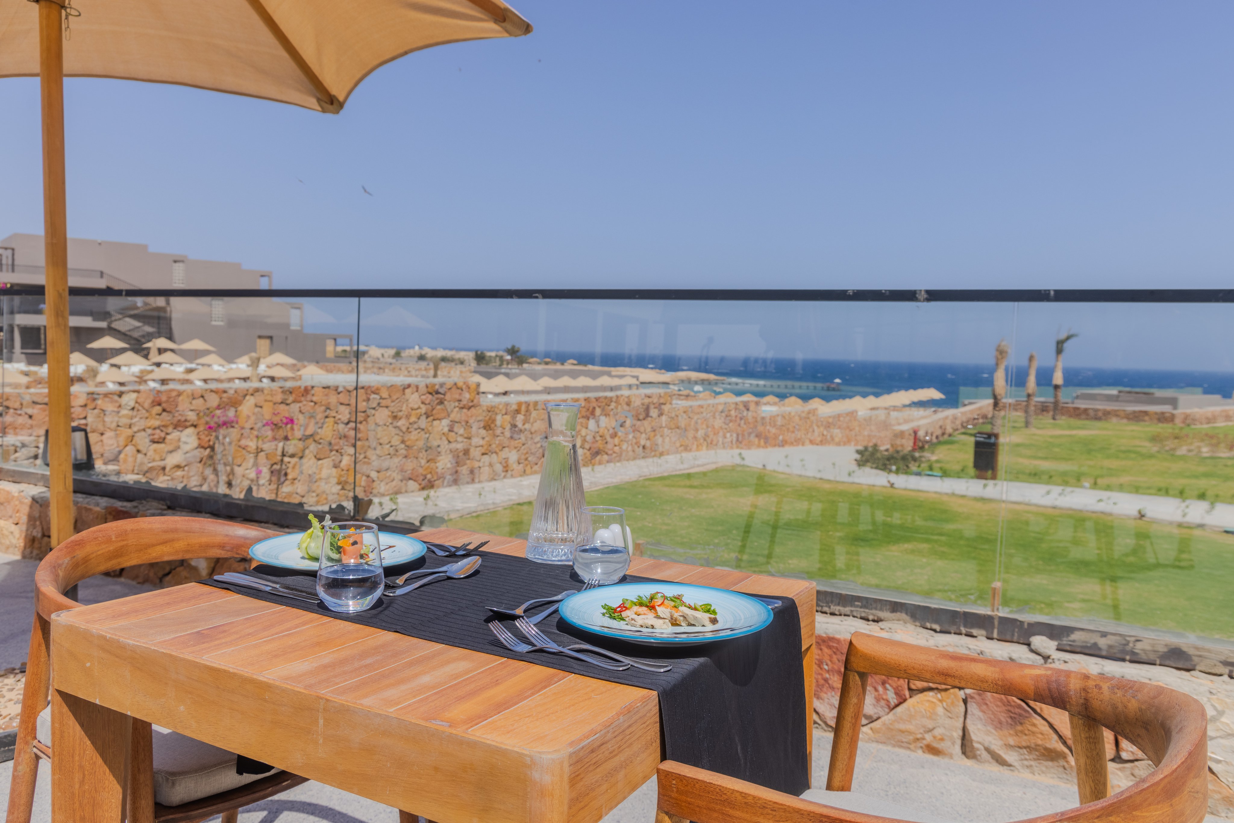 Ein gedeckter Tisch mit Blick auf eine grüne Urlaubslandschaft bei Sonnenlicht