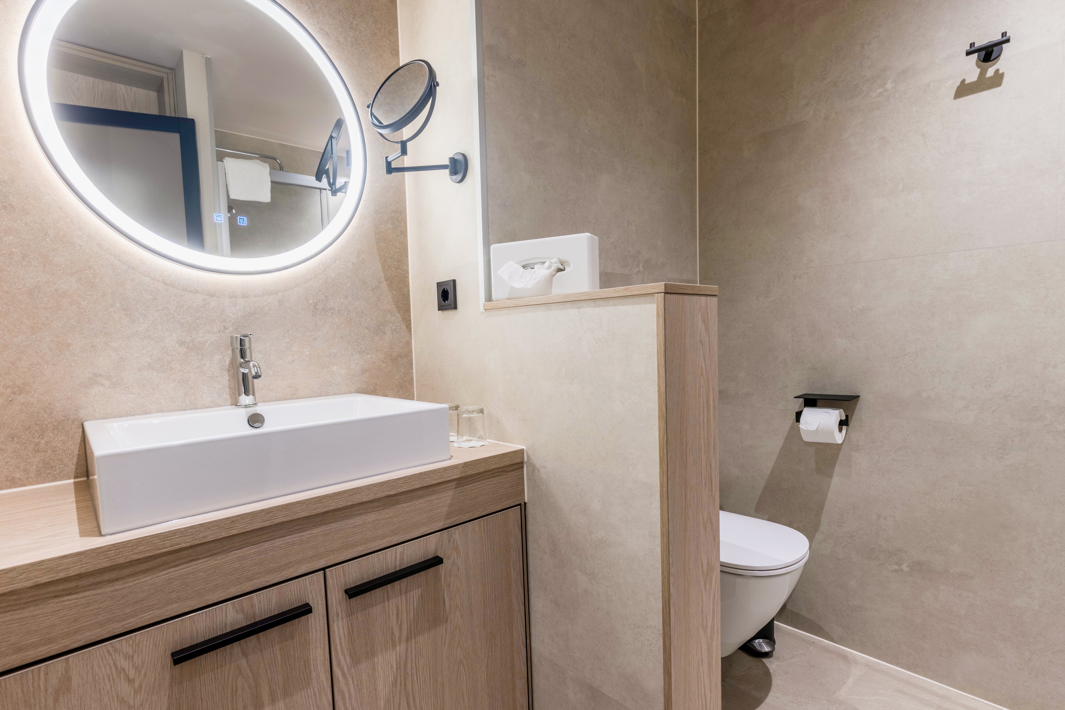 Helles modernes Badezimmer mit Waschtisch, Spiegel mit Beleuchtung und WC bei Aldiana