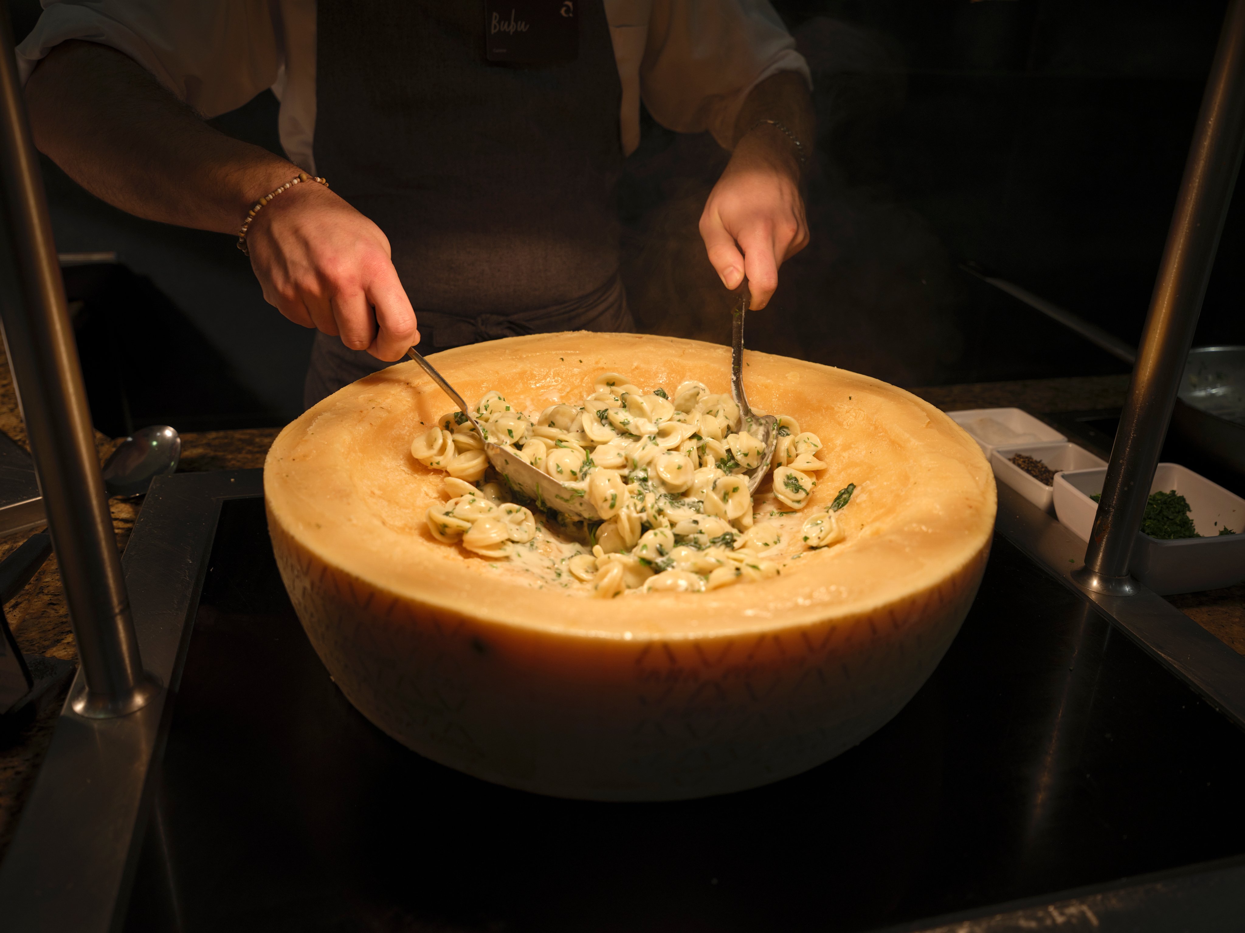 Ein Mann bereitet Pasta in einem großen Käse für einen Premium Cluburlaub bei Aldiana vor