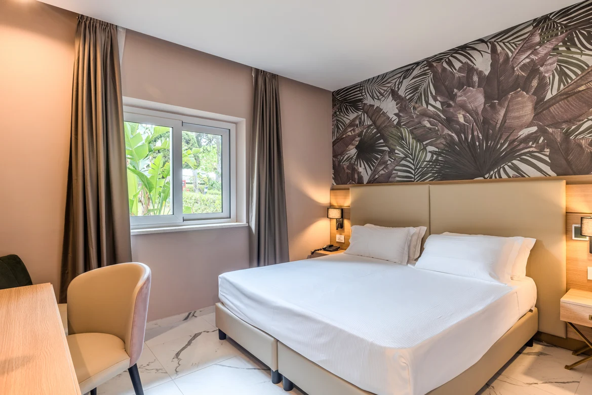 Modern Hotelzimmer mit Doppelbett, beigen Wänden und Fenster mit Vorhängen, entspannte Atmosphäre