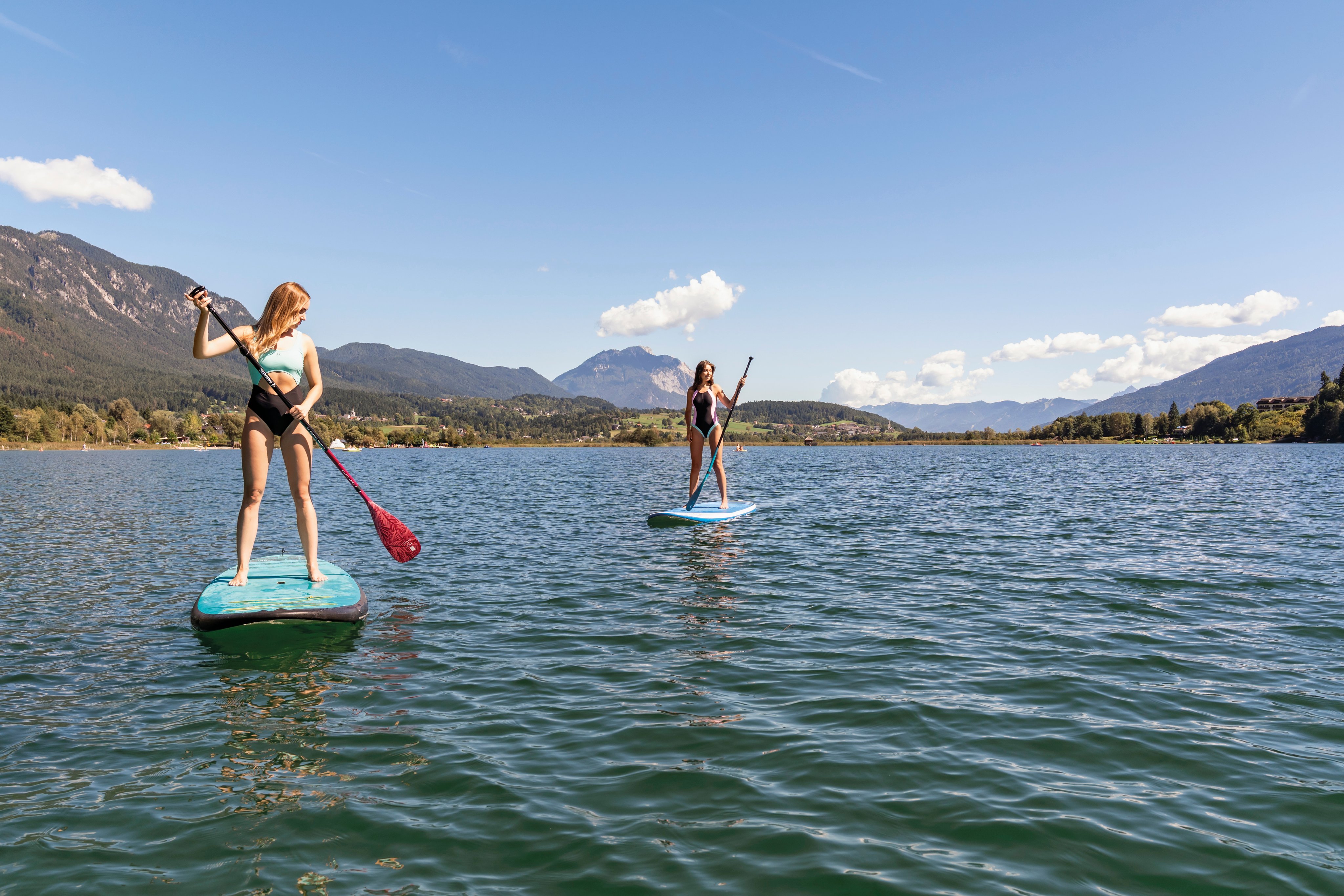 Zwei Frauen beim Stand-Up-Paddle-Boarden auf einem See vor Bergen bei Aldiana Premium Cluburlaub