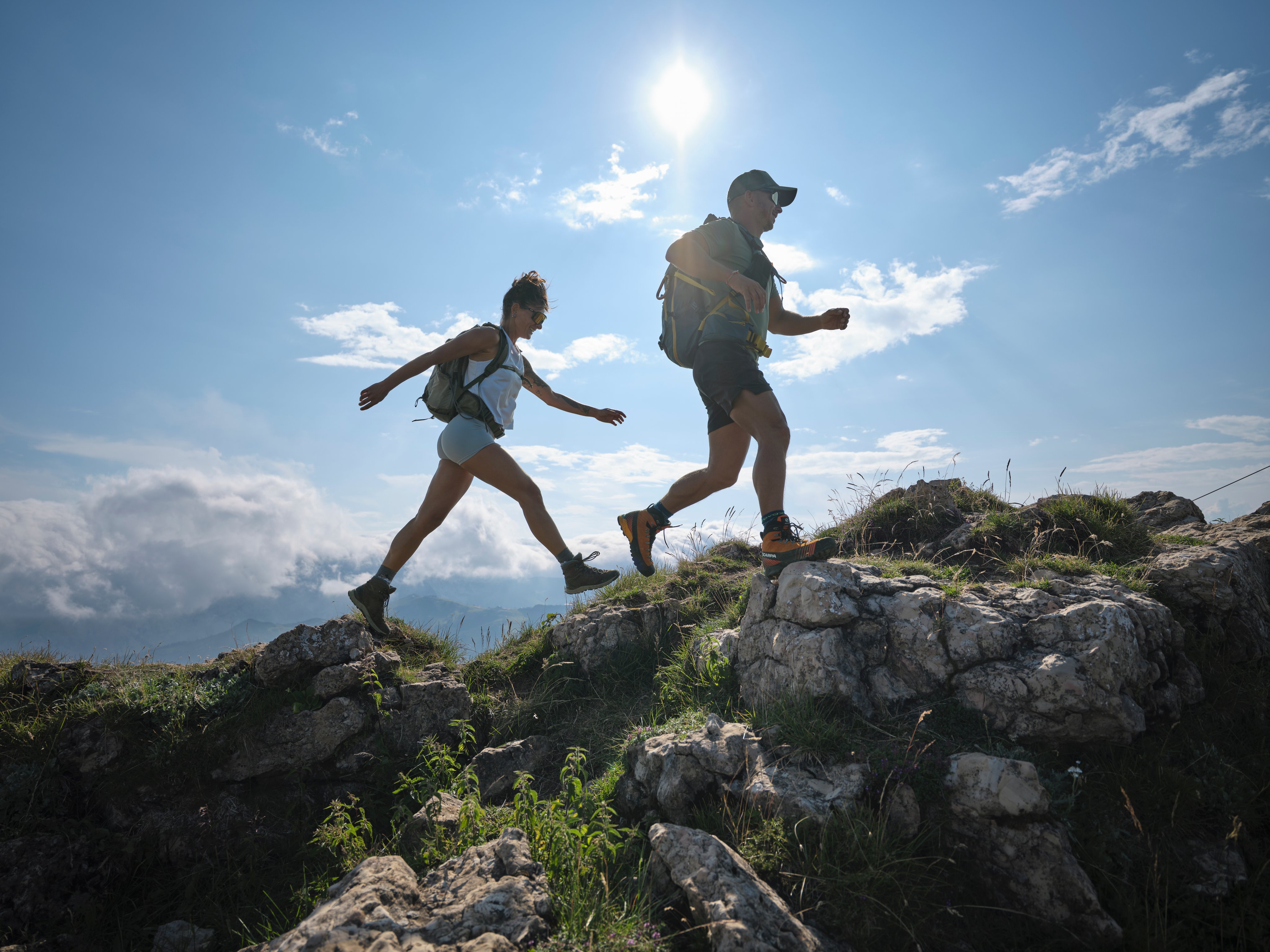 Zwei hikers auf felsiger Bergkuppe bei Sonnenschein, junge Erwachsene im Abenteuerurlaub