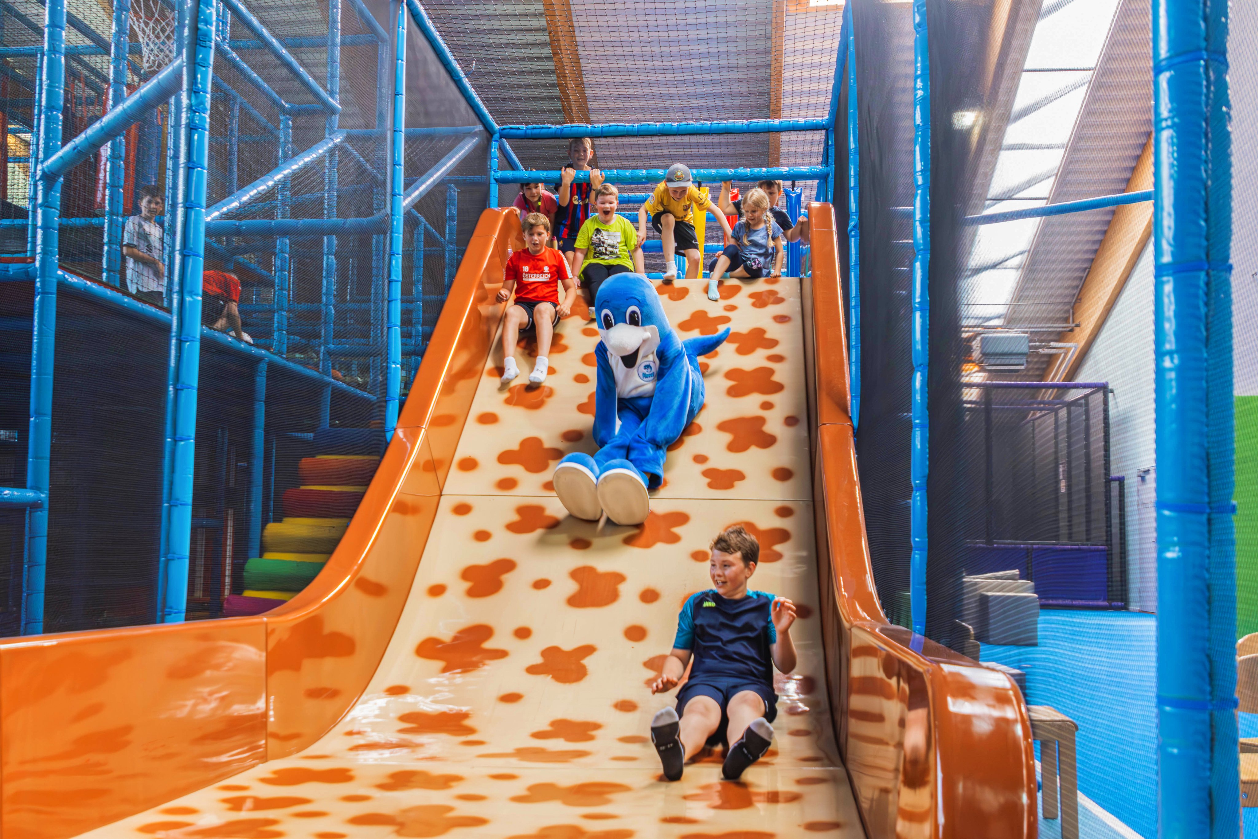Kinder spielen auf einer bunten Rutsche in einer sicheren Indoor-Spielanlage bei Aldiana, Premium Cluburlaub