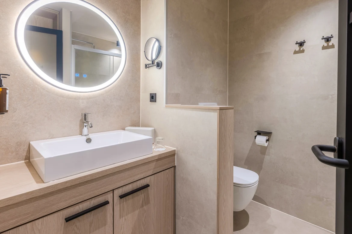 Moderne Badezimmer mit Holzschrank, Waschbecken und großem Spiegel, barrierefrei gestaltet