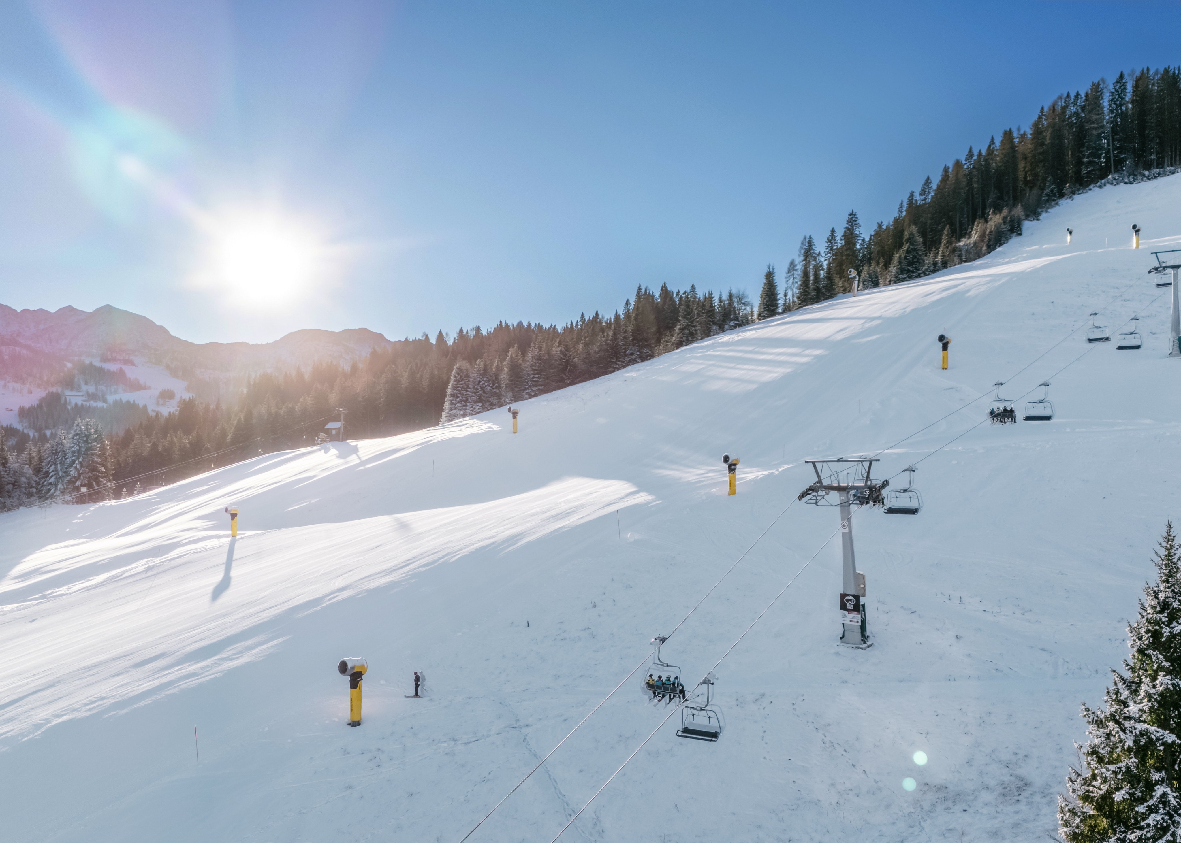 Skisesselbahn im verschneiten Alpenurlaubsgebiet bei Sonnenlicht, winterliches Skigebiet