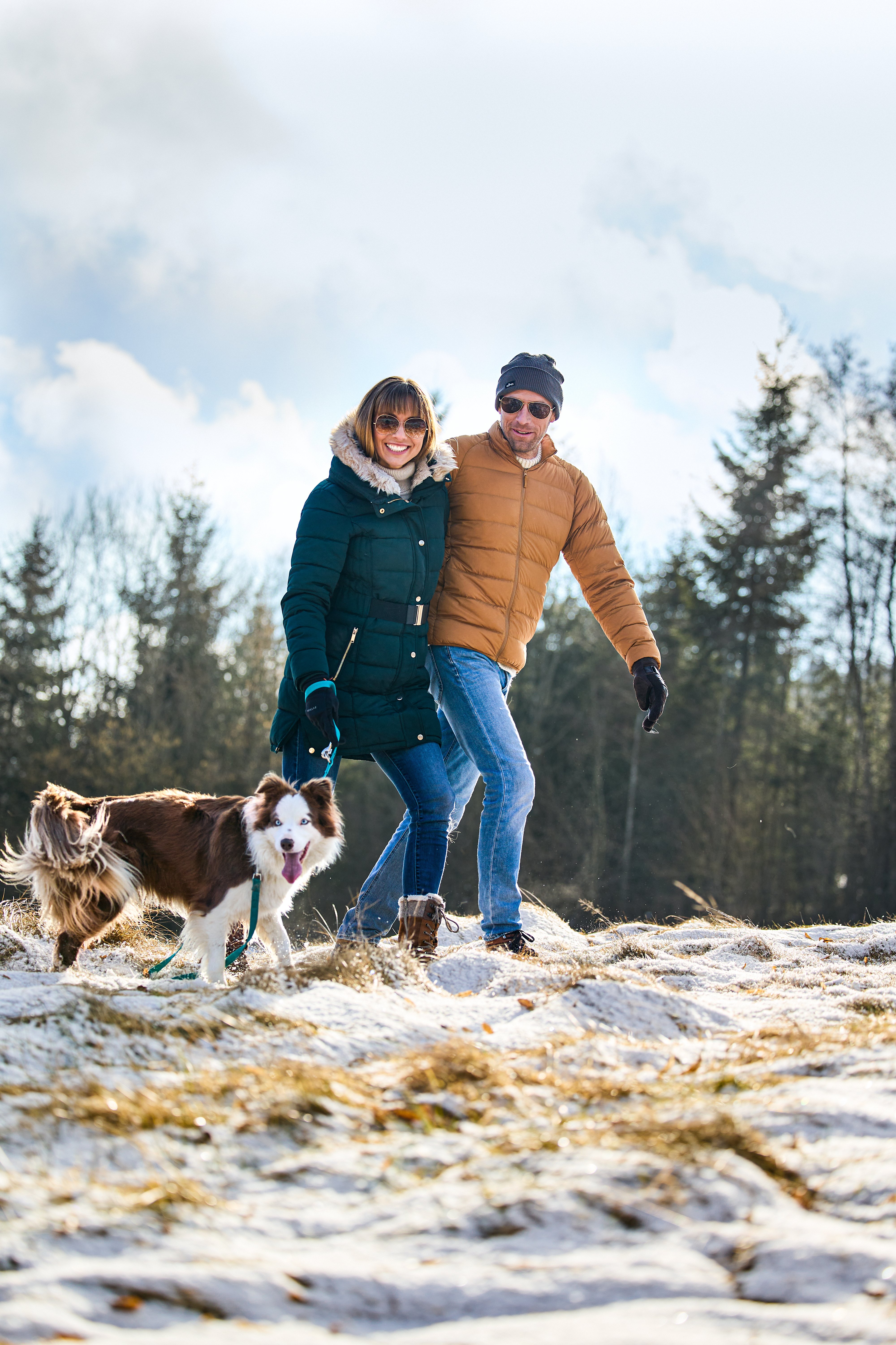 Zwei Menschen gehen mit Hund im Schnee im Aldiana Premium Cluburlaub in der Natur