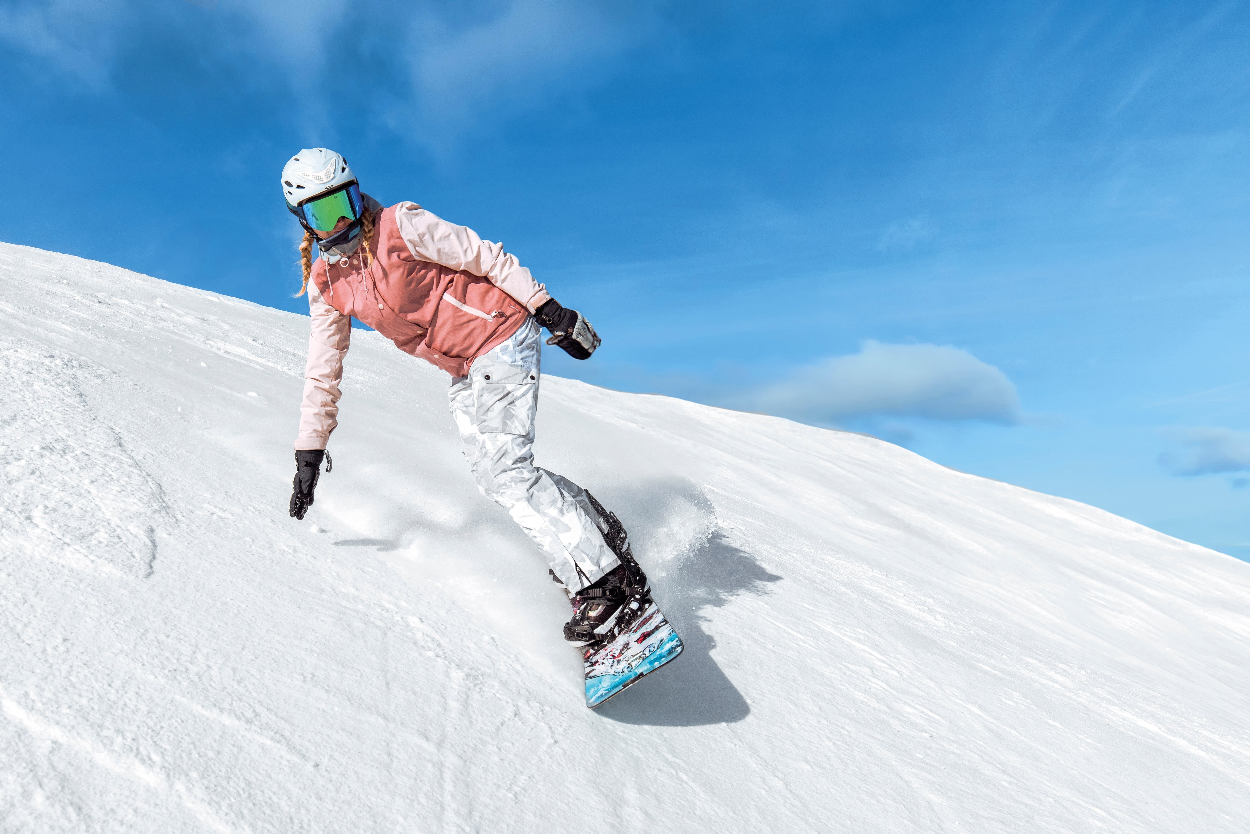 Skifahrer in Sonnenbrille und Helm auf verschneitem Hang bei schönem Himmel