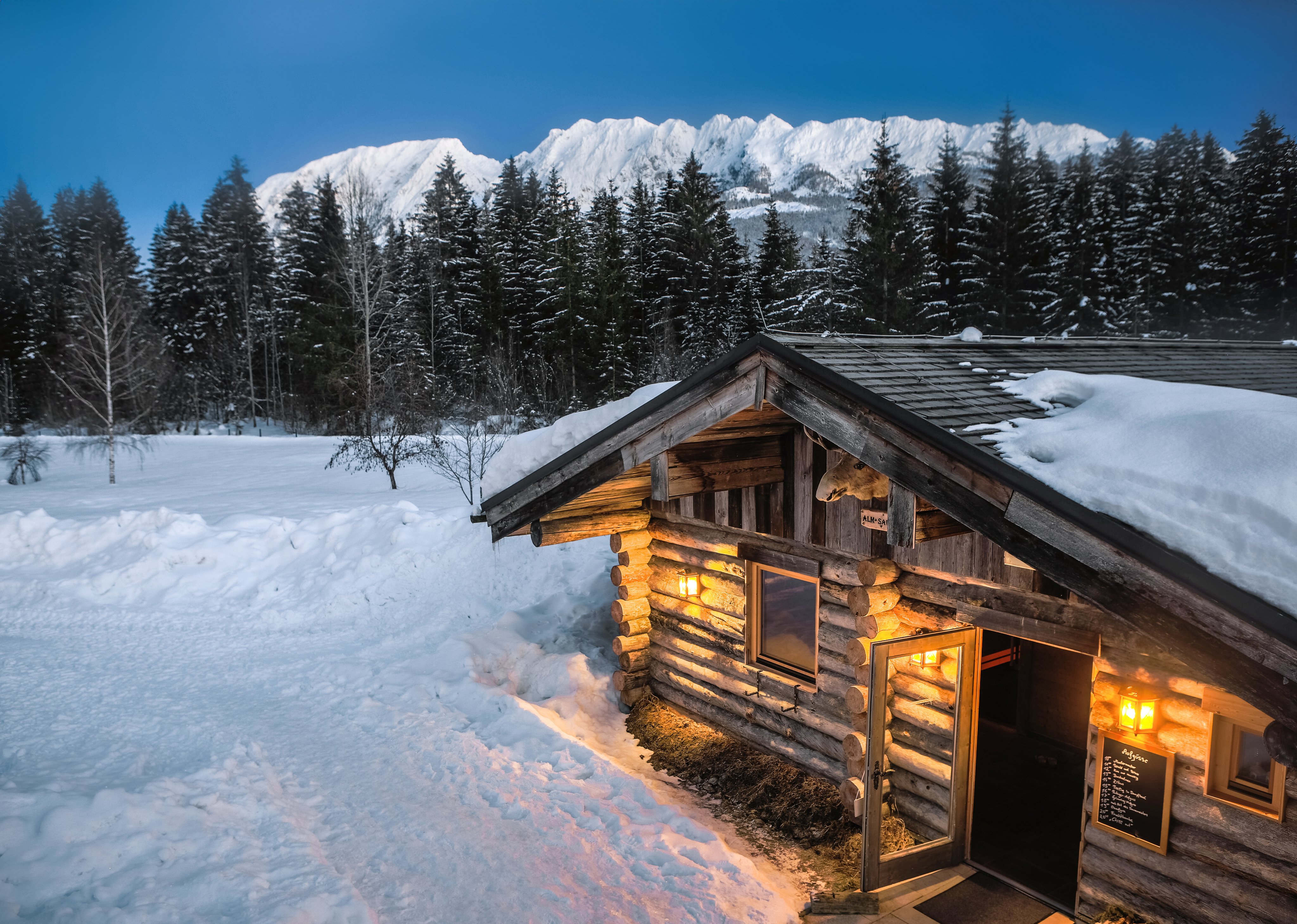 Gemütliche Holzhütte im verschneiten Wald mit Bergblick, ideal für Premium Cluburlaub bei Aldiana