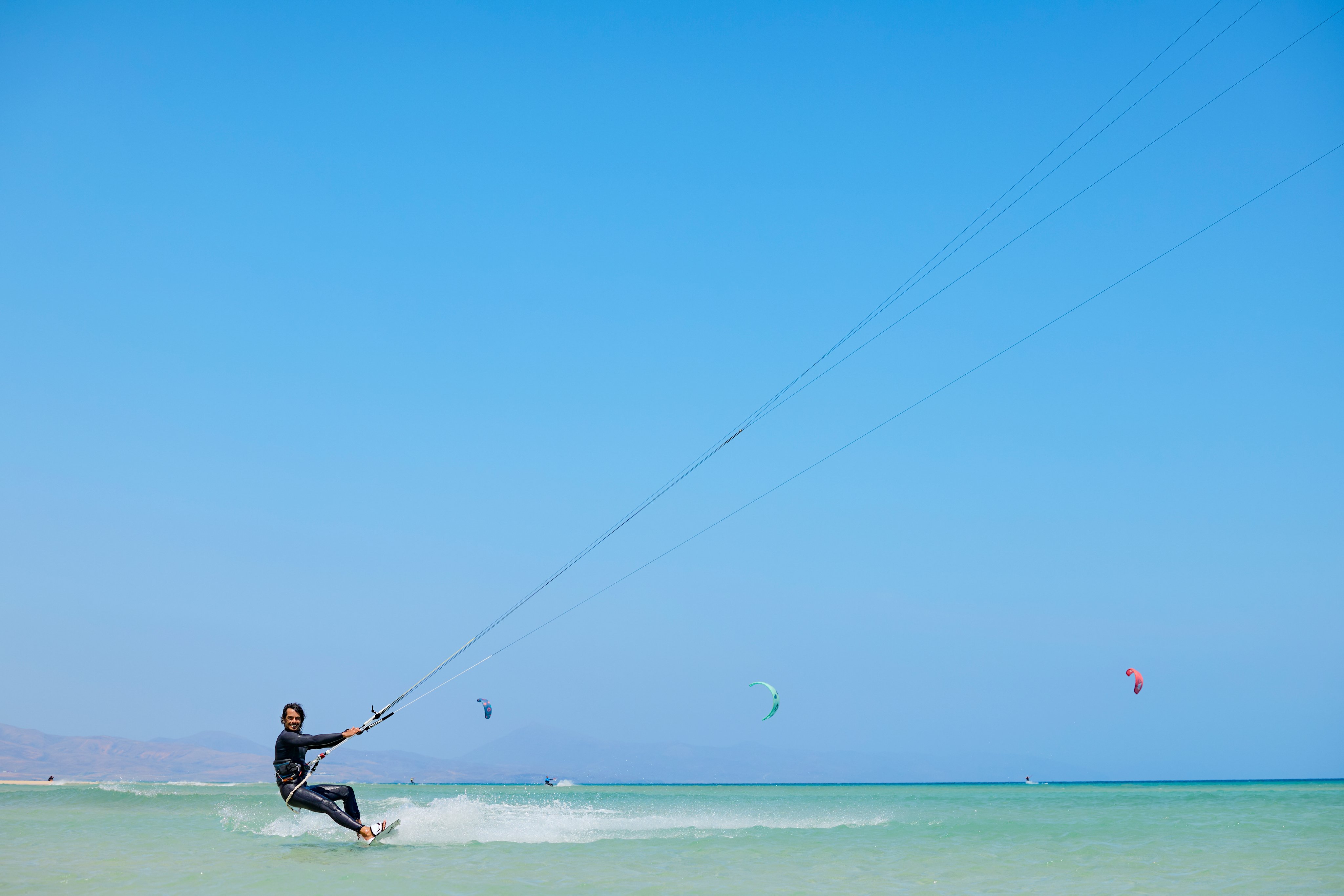 Mann beim Kitesurfen am Strand, blauer Himmel, Wasser, urlaub bei Aldiana, Premium Cluburlaub