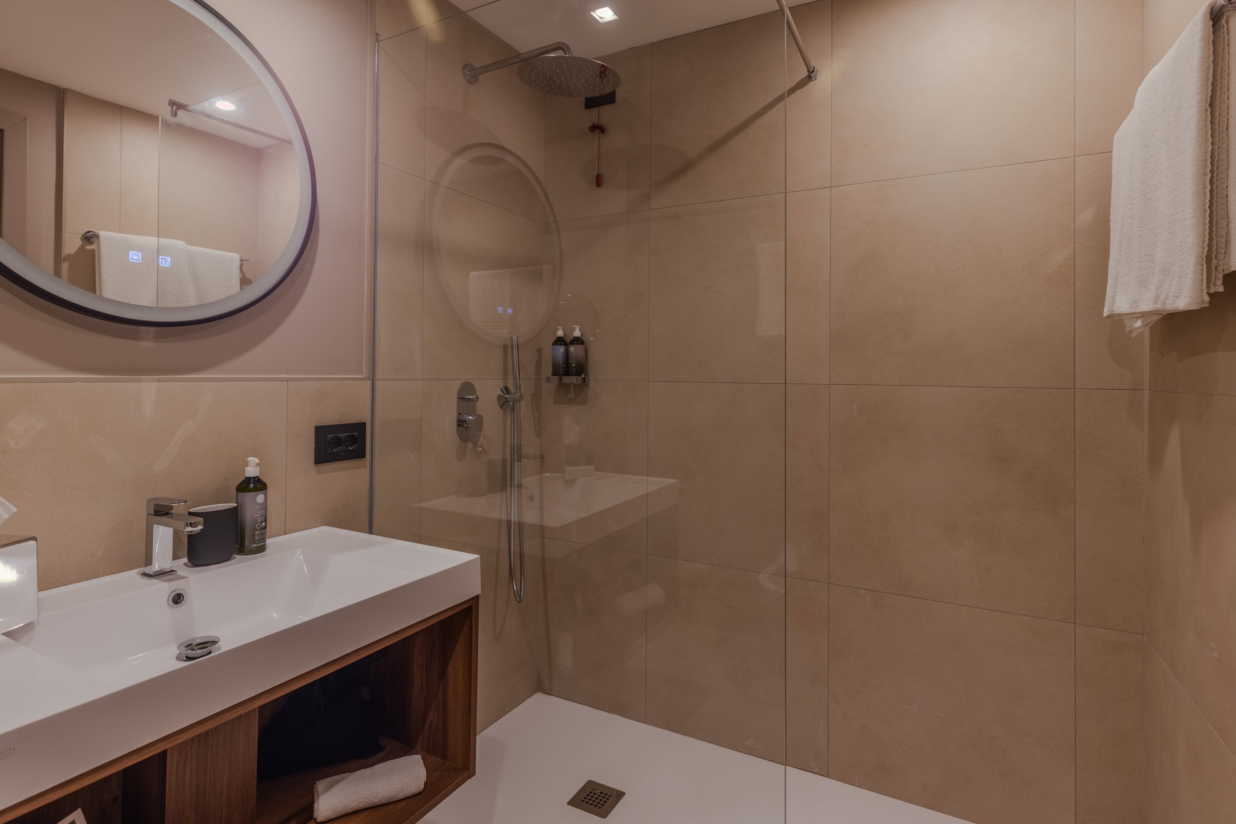 Badezimmer im Amber Hotel mit Waschbecken, Spiegel und begehbarer Dusche