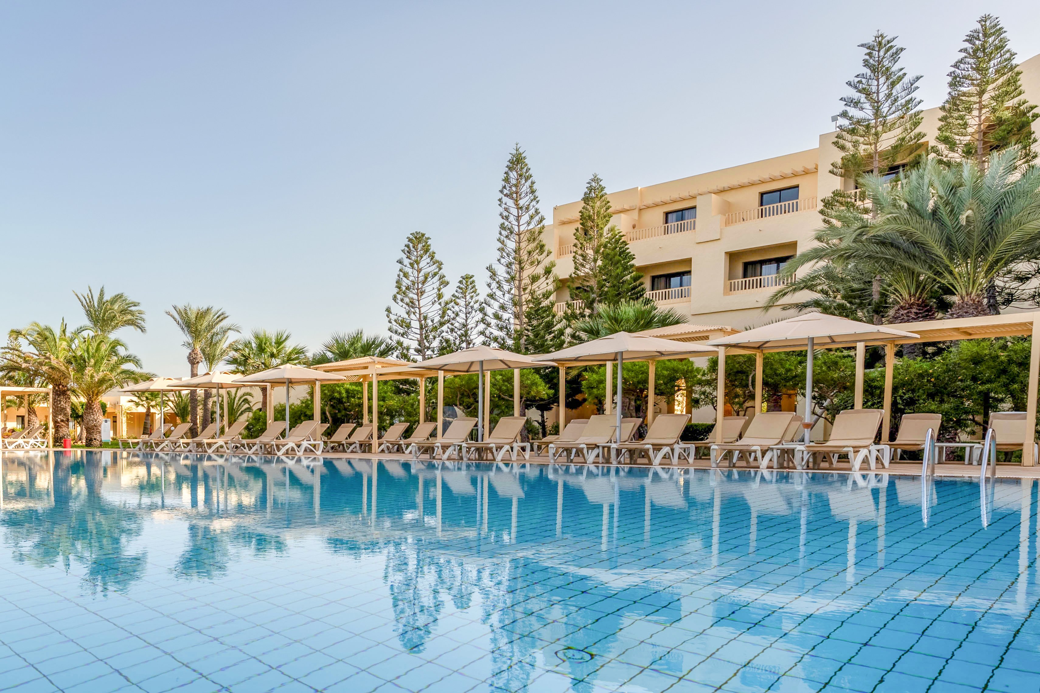 Hotelanlage mit Pool, Liegestühlen und Sonnenschirmen