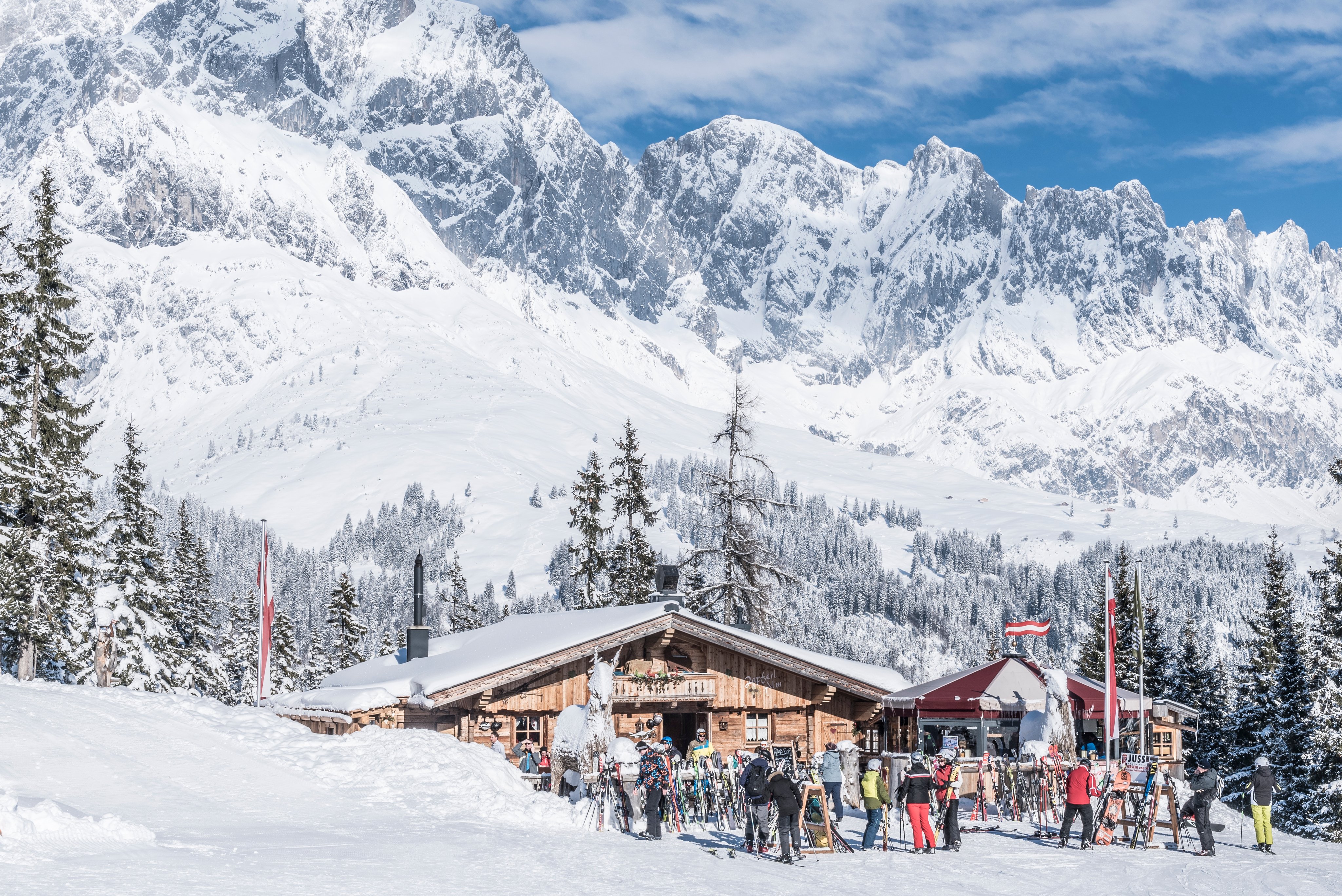 Ein verschneiter Bergort mit Holzhaus und Skigästen im österreichischen Alpenraum