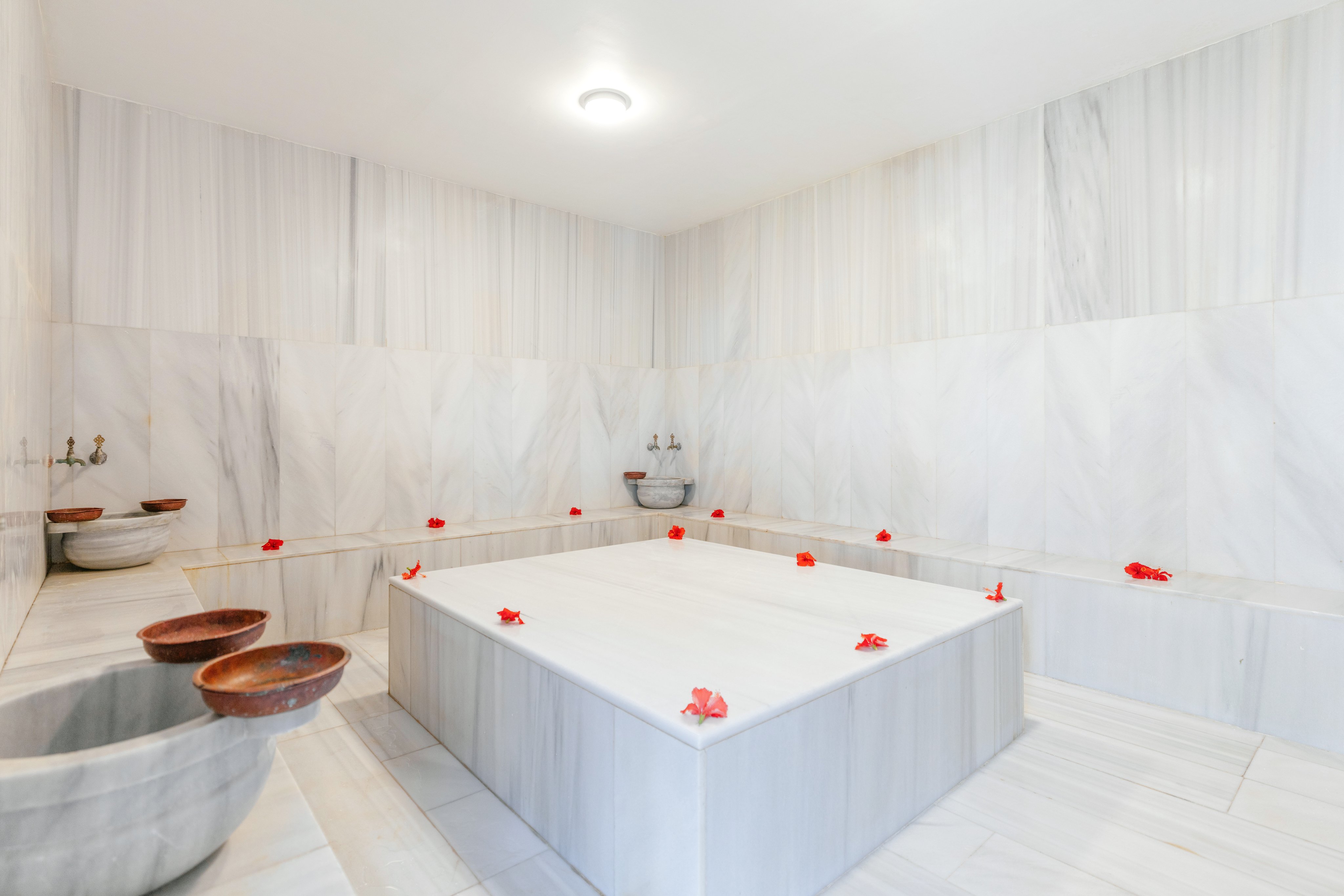 Helles Saunabad mit weißen Marmorwänden und roten Blumen für Entspannung bei Aldiana