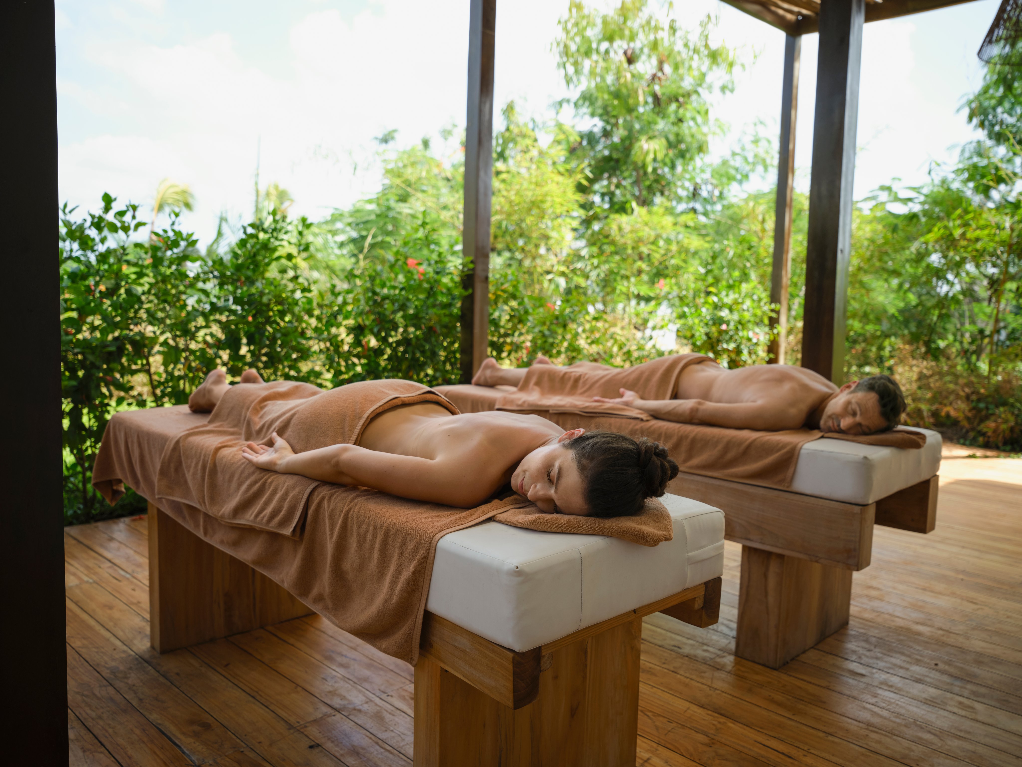Zwei Menschen bei einer Wellness-Behandlung in einer holzgedeckten Ruheoase
