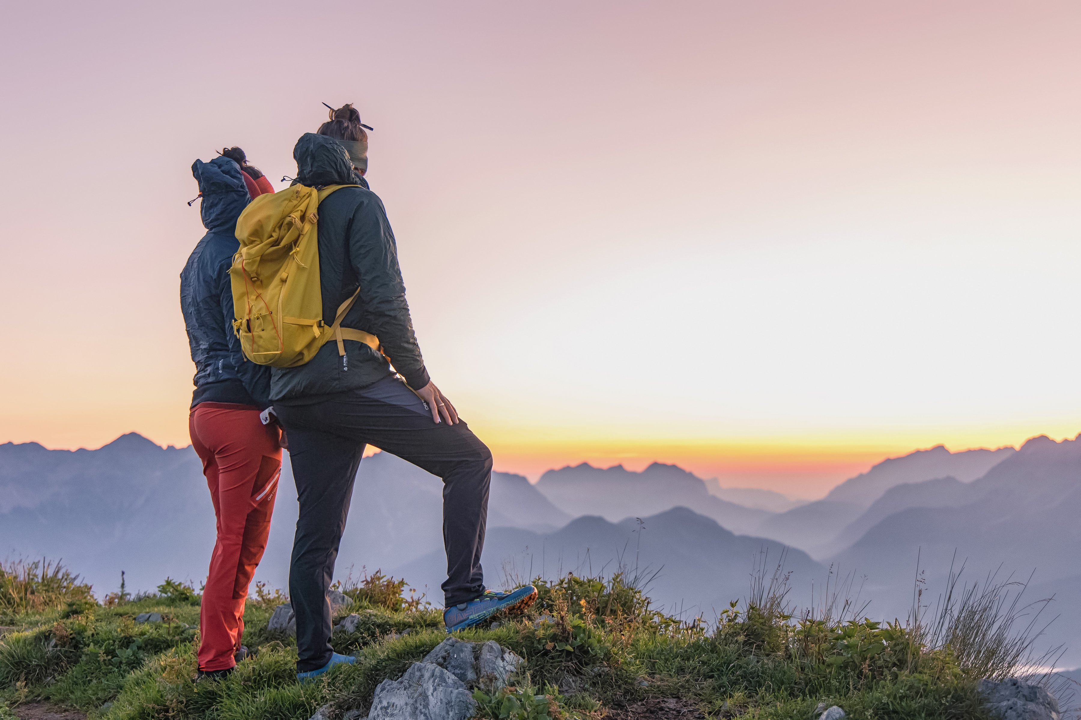 Zwei Wanderer mit Rucksack im Gebirge bei Sonnenuntergang, genießen die Natur.