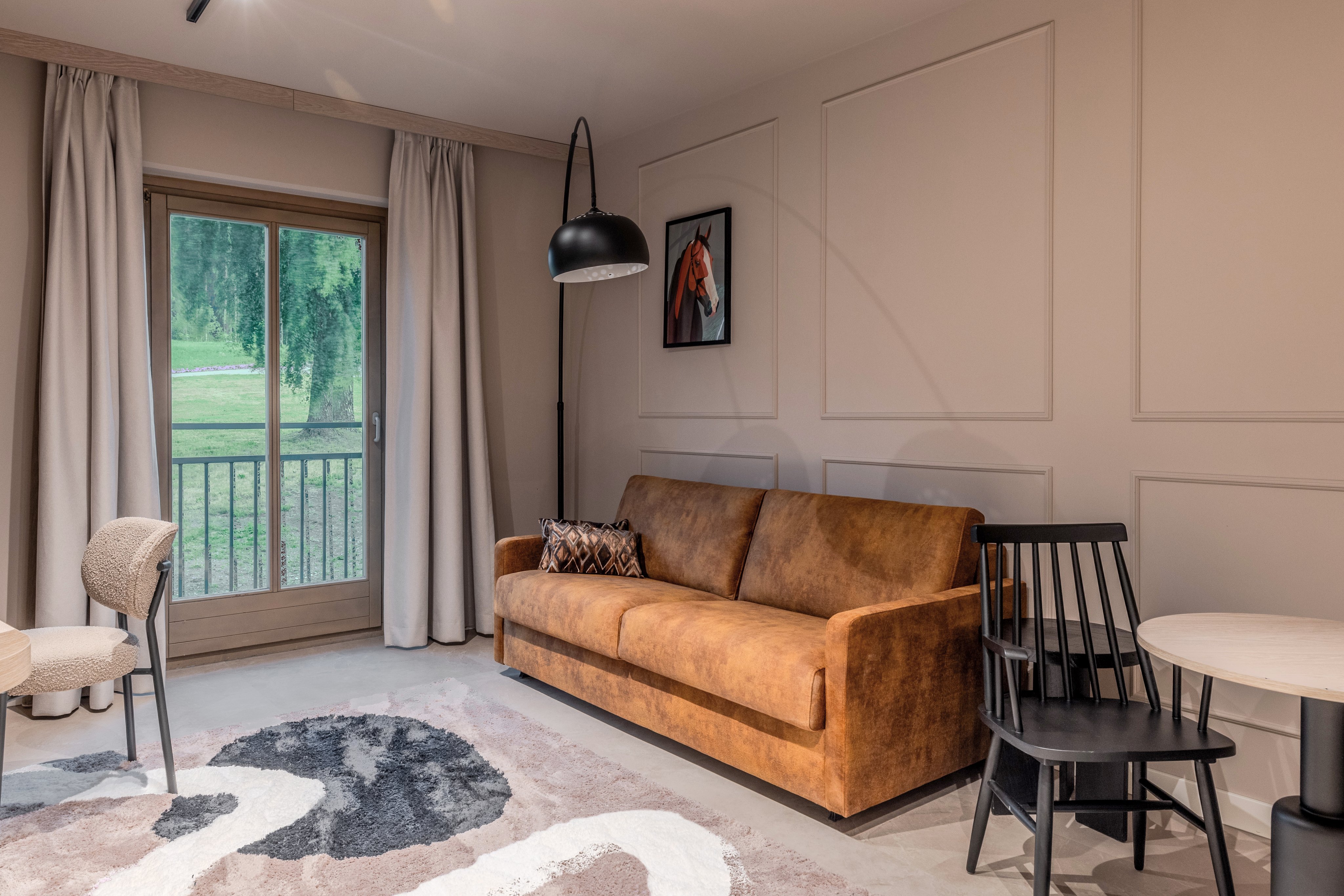 Gemütliches Wohnzimmer mit braunem Sofa, großen Fenstern und modernem Dekor