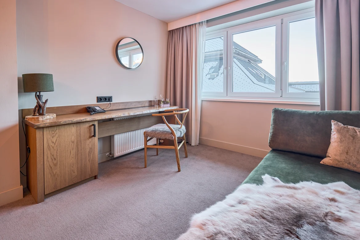 Ein elegantes Hotelzimmer mit Schreibtisch, Fenster und gemütlichem Sofa, komfortabler Urlaubsraum