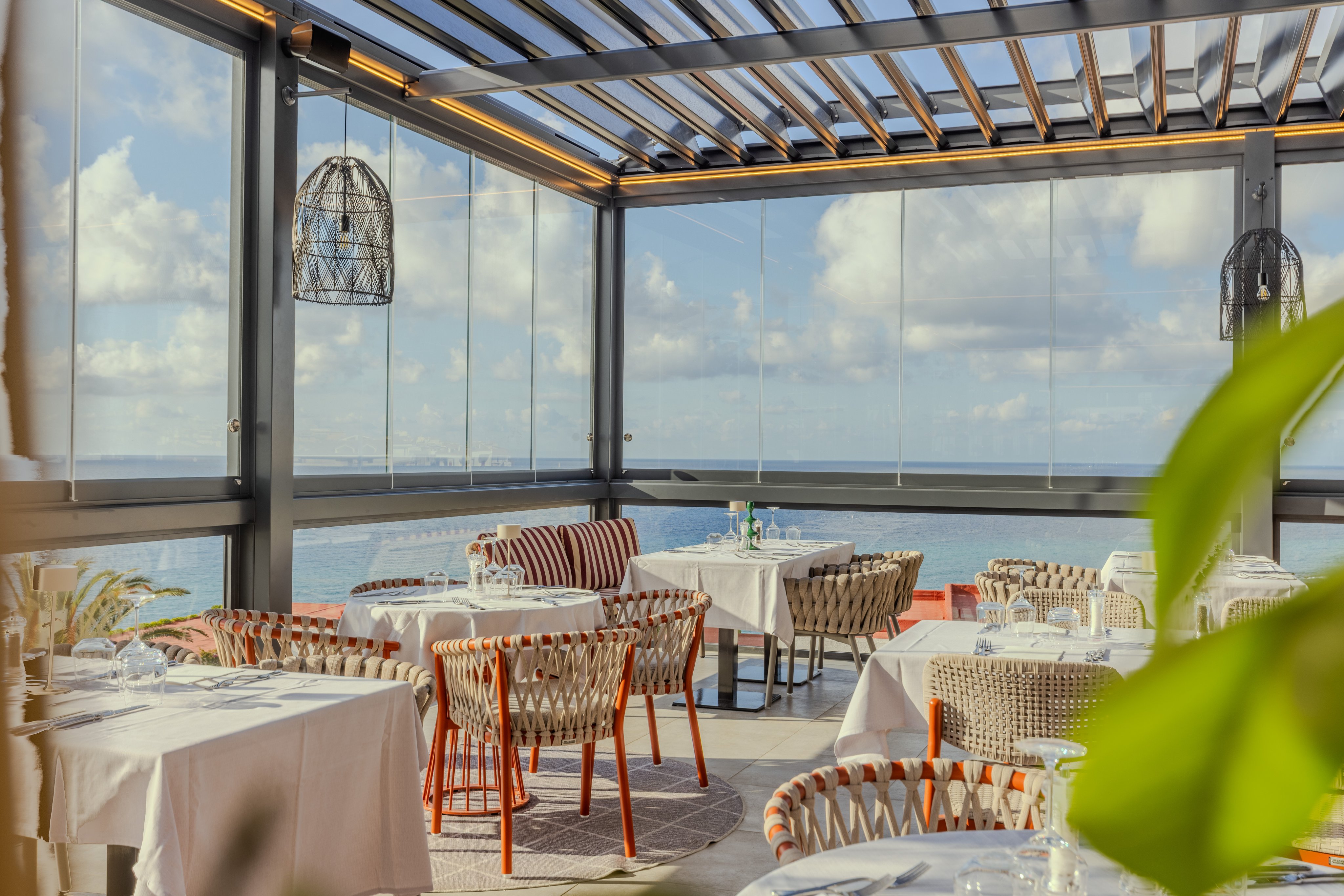 Heller Wintergarten mit Blick auf den Himmel und Meeresblick, elegante Sitze und Tische