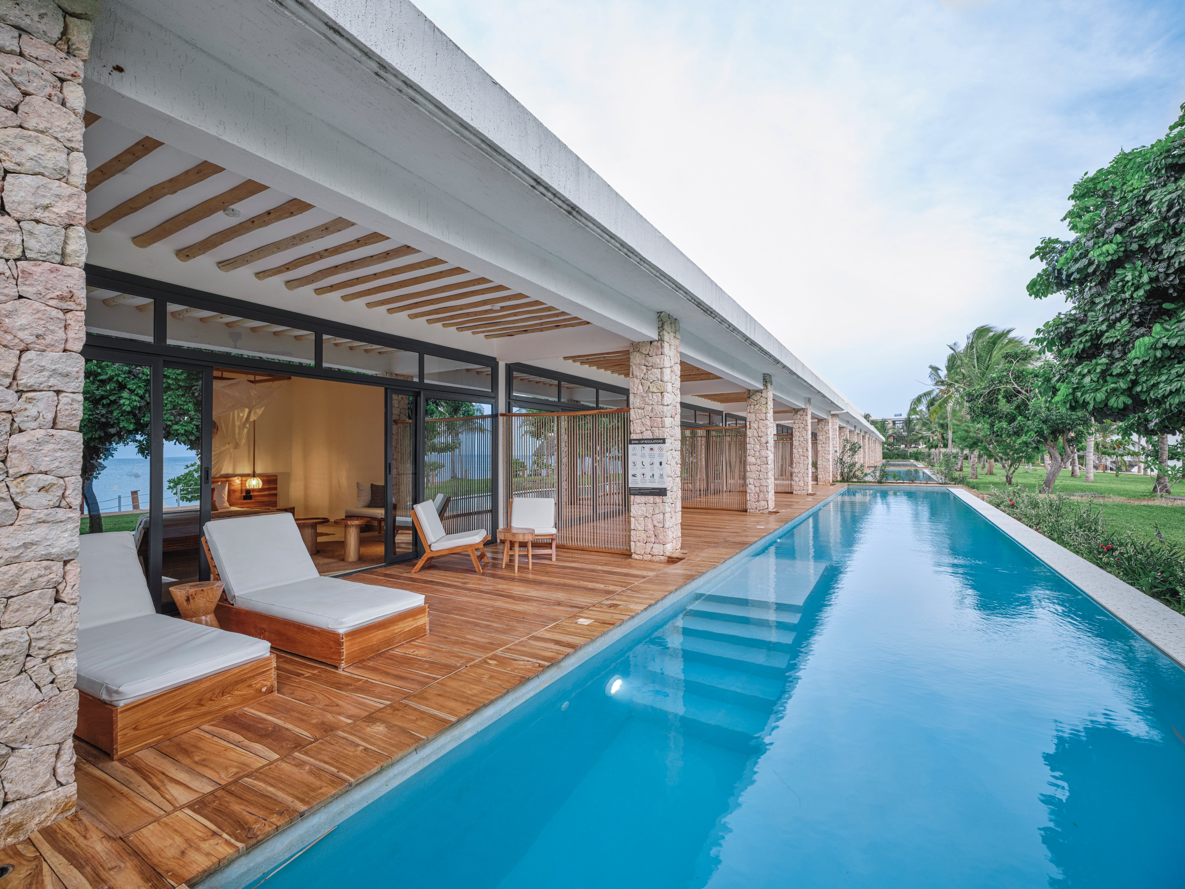 Ein moderner Poolbereich bei Aldiana mit Liegestühlen und Blick auf grüne Natur
