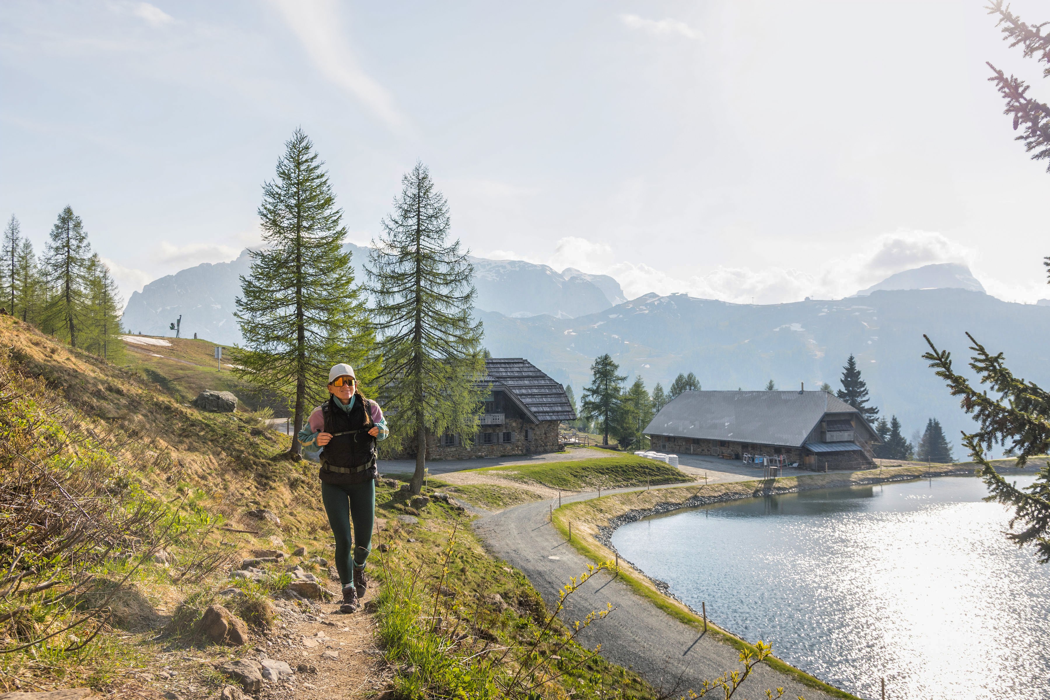 Ein Mann wandert entlang eines Sees in der Natur bei Aldiana, umgeben von Bäumen und Bergen